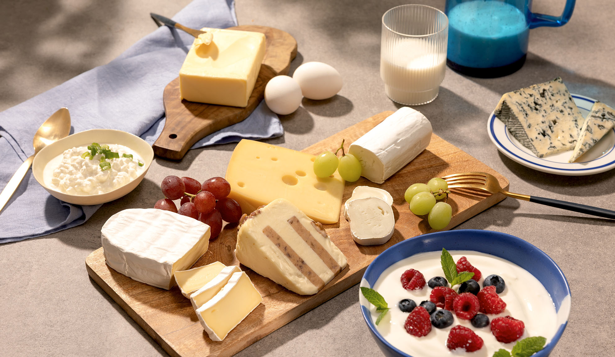 Különféle sajtok, szőlő és tejtermékek, mint túró, tej és joghurt bogyós gyümölcsökkel.