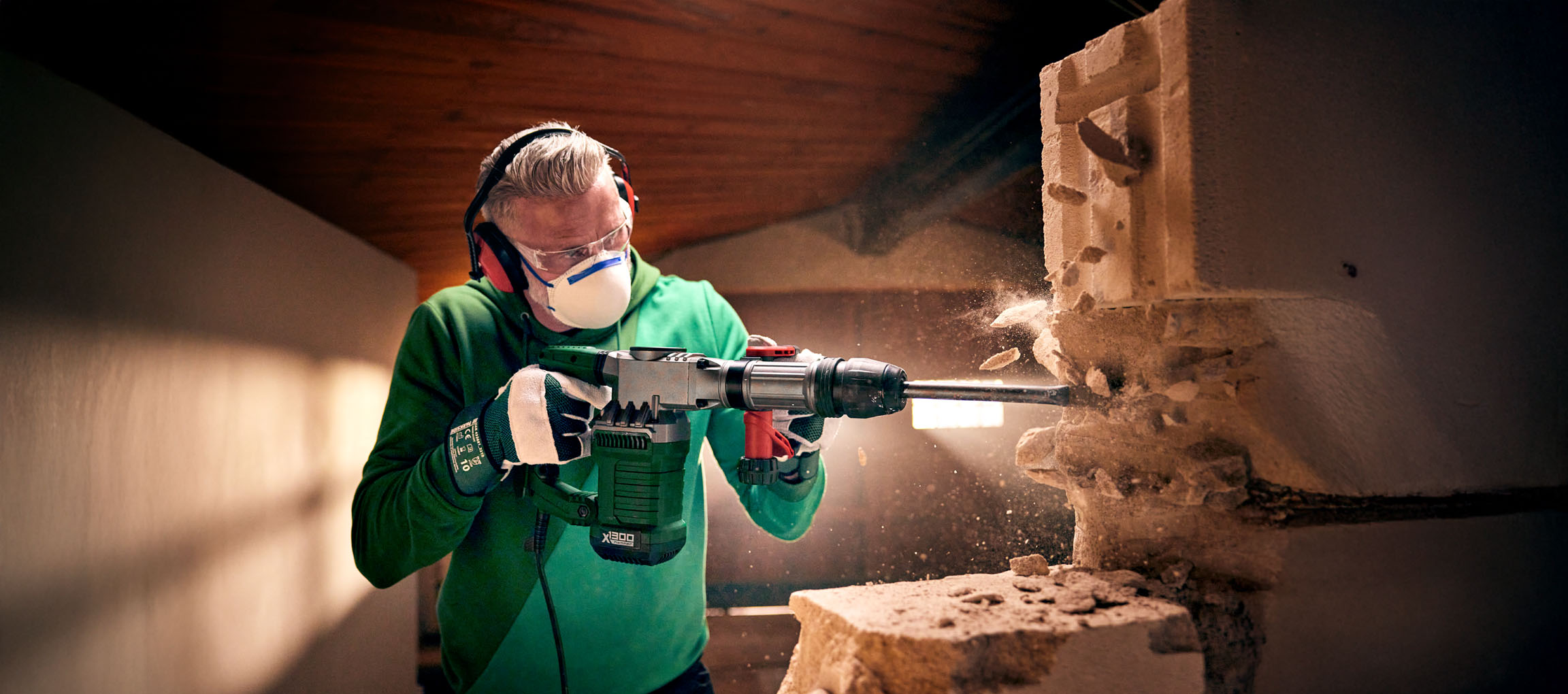 Egy férfi Bosch X1300 bontókalapáccsal bont egy betonblokk falat.