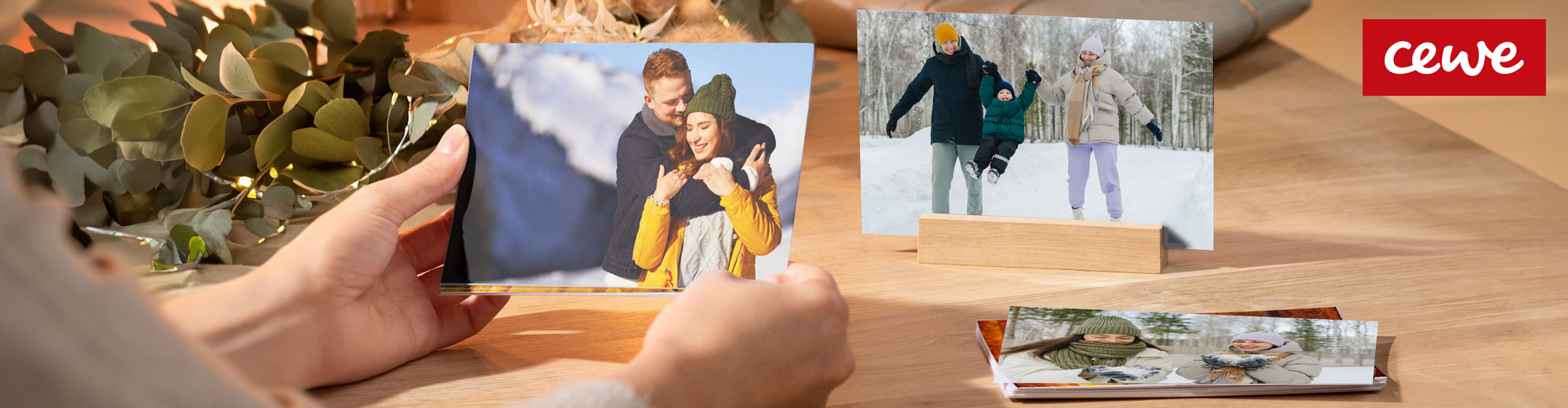 CEWE fotótermékek: egy pár és egy család téli képei, egy nő kezében tartja az egyiket.