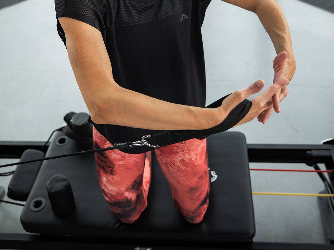 Nő edz ellenállás gumiszalagokkal egy Pilates gépen.