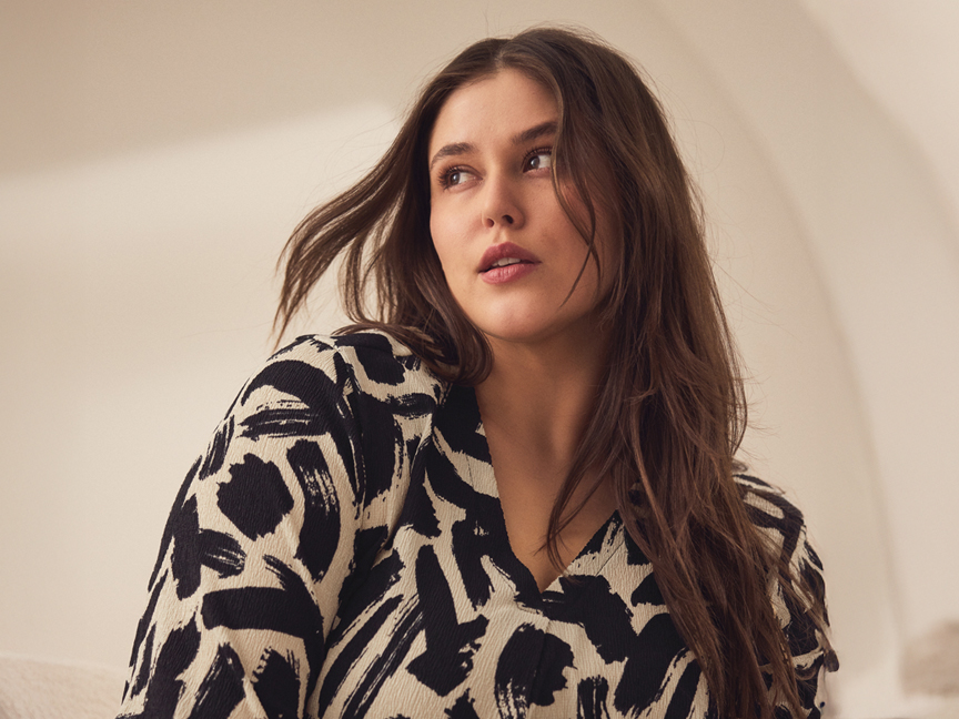 Plus size modell egy elegáns, fekete-fehér mintás ruhában.