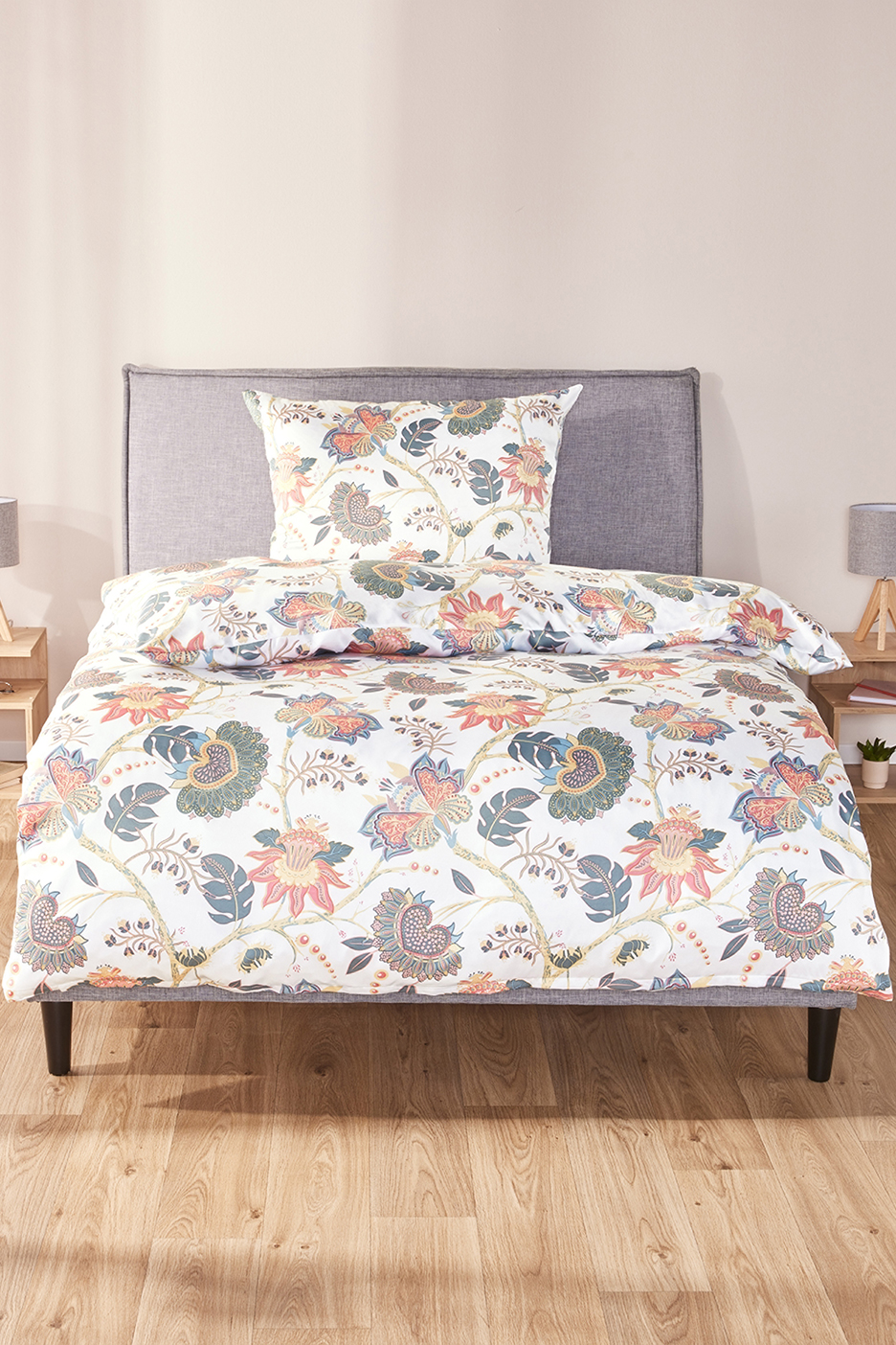 Fehér ágynemű virágmintával, szürke ágykereten, fa padlón