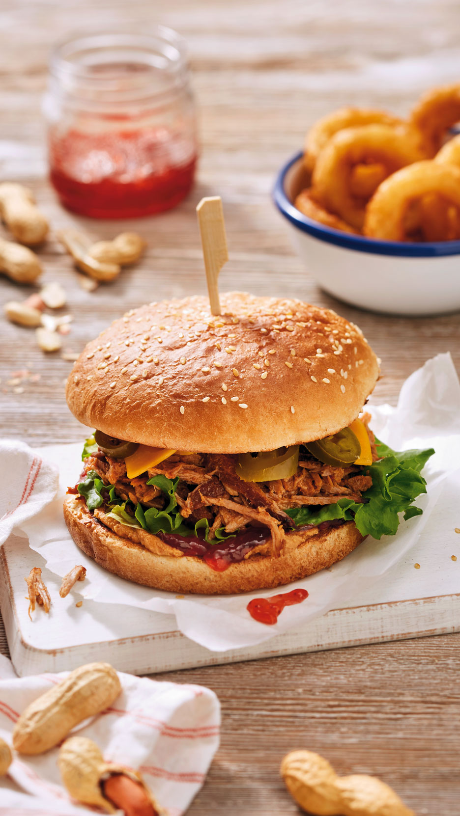 Pulled pork burger sajttal, jalapeñóval és salátával, hagymakarikákkal és mogyoróval.