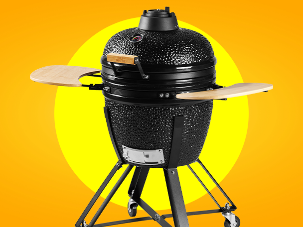 Fekete kerámia grill oldalsó polcokkal, narancssárga és sárga háttérrel.