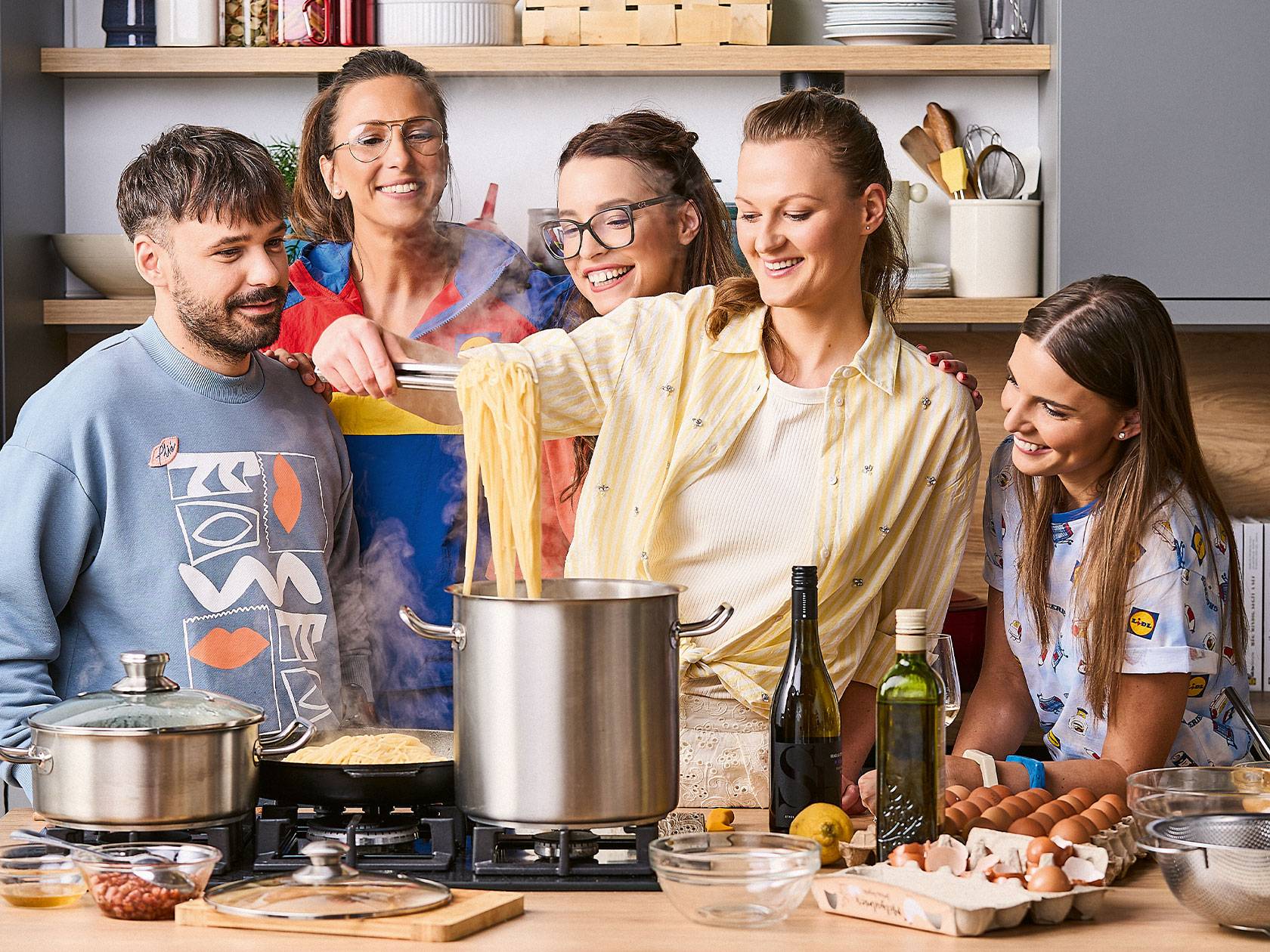 Öt barát főz tésztát a konyhában, Lidl márkájú pólóban.