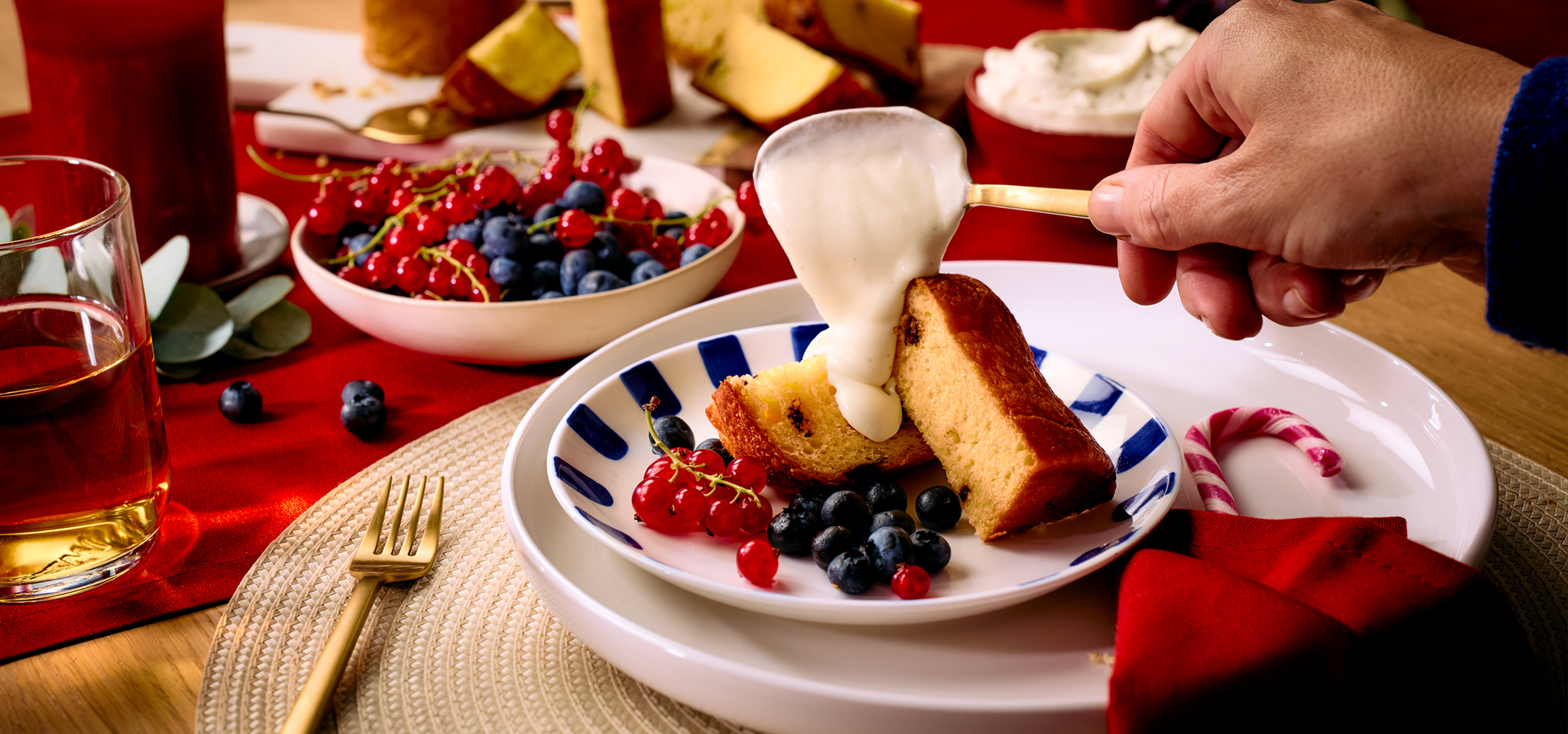 Sütemény vaníliasodóval, bogyós gyümölcsökkel és teával egy piros asztalon.