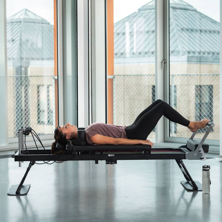 Nő Pilates gyakorlatot végez reformer gépen.