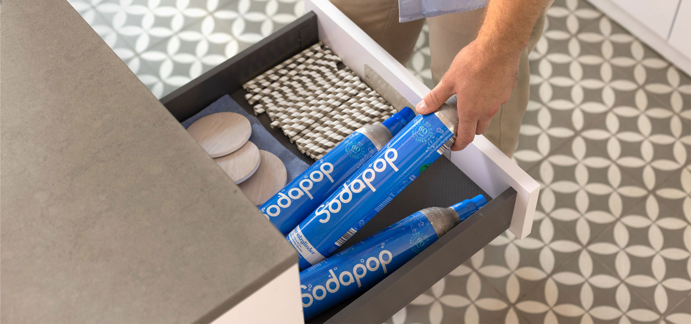 Sodapop szódapatronok egy fiókban, mellette szívószálak és alátétek.