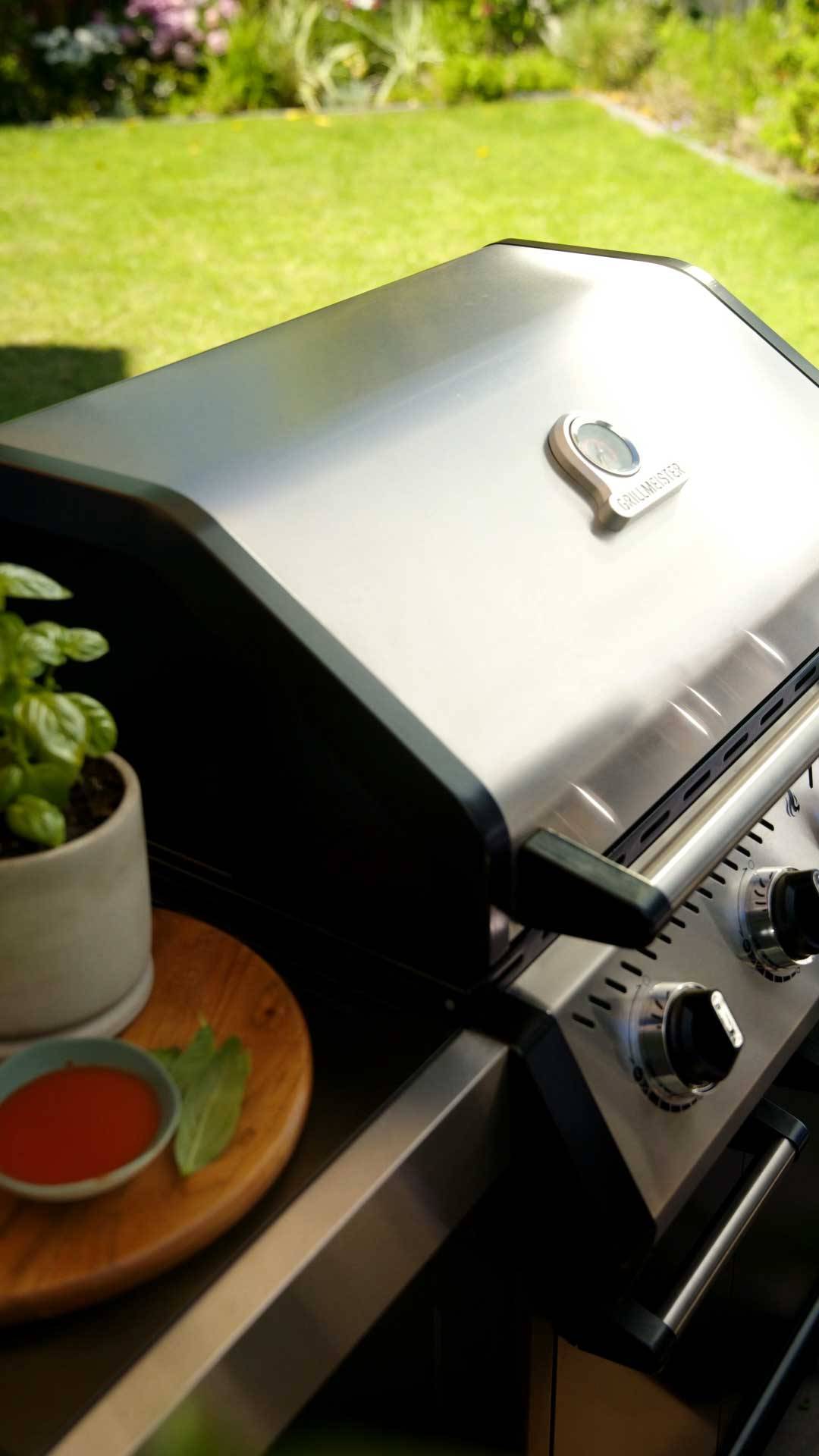 Rozsdamentes acél gázgrill hőmérővel, bazsalikommal és szósszal.