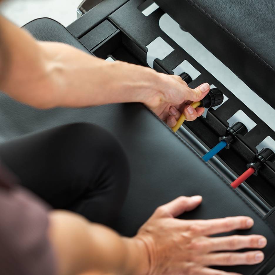 Személy állít ellenállási szalagokat egy edzőpadon.