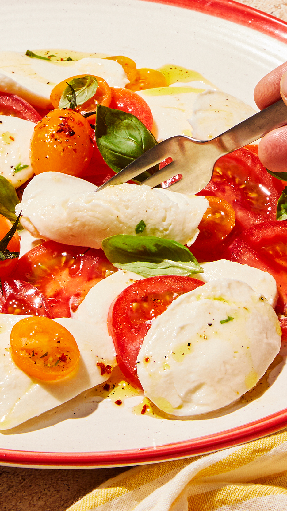 Caprese saláta paradicsommal, mozzarellával és bazsalikommal, villával szúrva.
