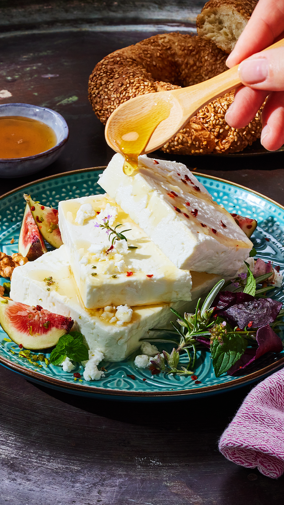 Feta sajt mézzel, fügével és zöldfűszerekkel, háttérben szezám pereccel.