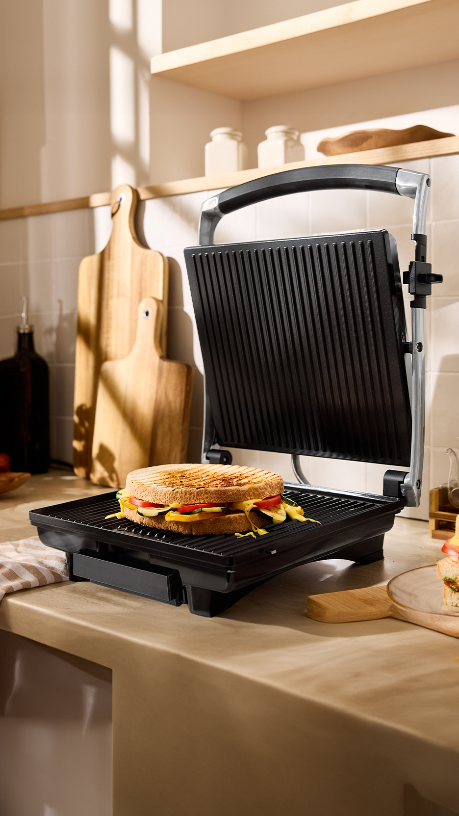 Grillszendvics zöldségekkel egy szendvicssütőben, konyhai környezetben.