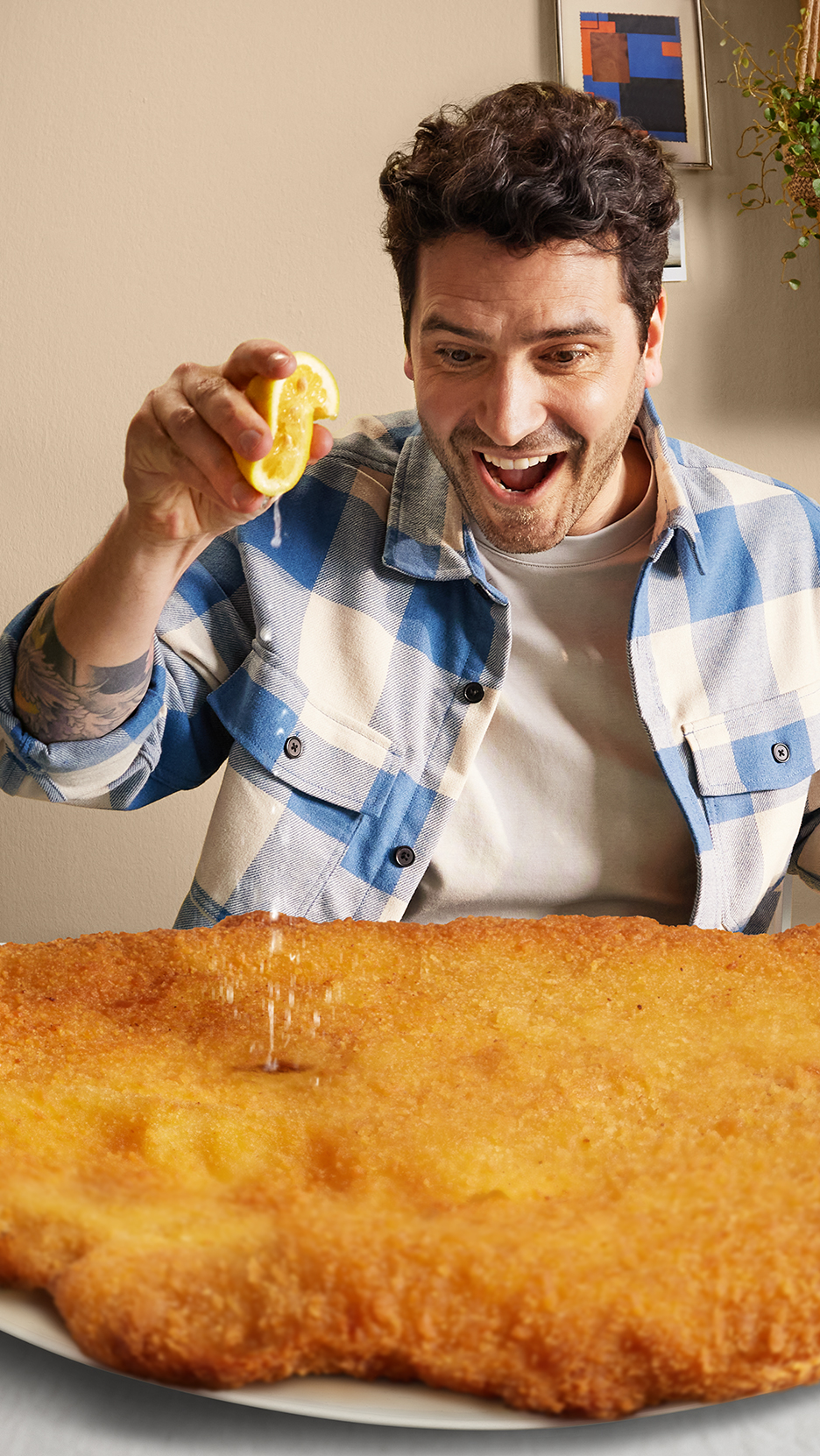 Egy férfi citromot facsar egy hatalmas rántott húsra, izgatottan nézve.