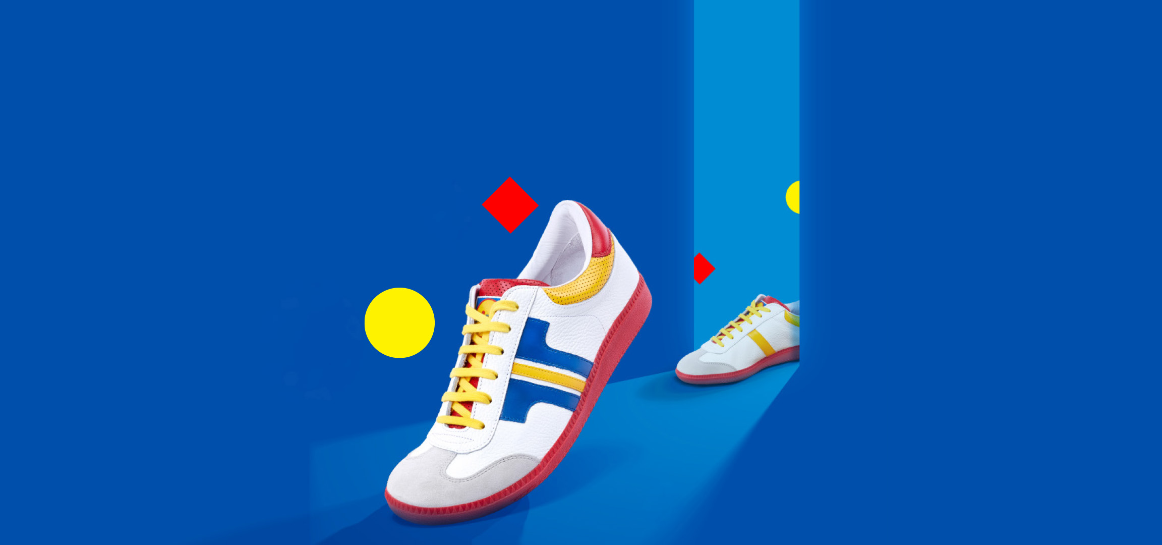 Fehér sportcipők kék háttér előtt, sárga és piros részletekkel.