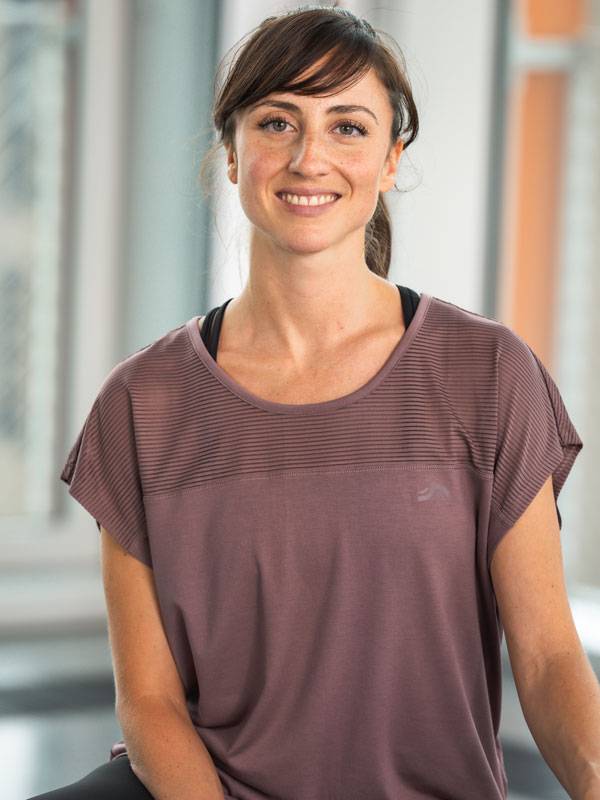 Mosolygó nő rövid ujjú lila sportfelsőben.