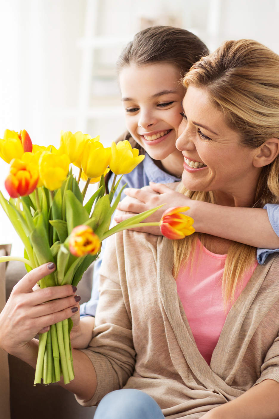 Anya és lánya mosolyogva tartanak egy csokor sárga tulipánt.
