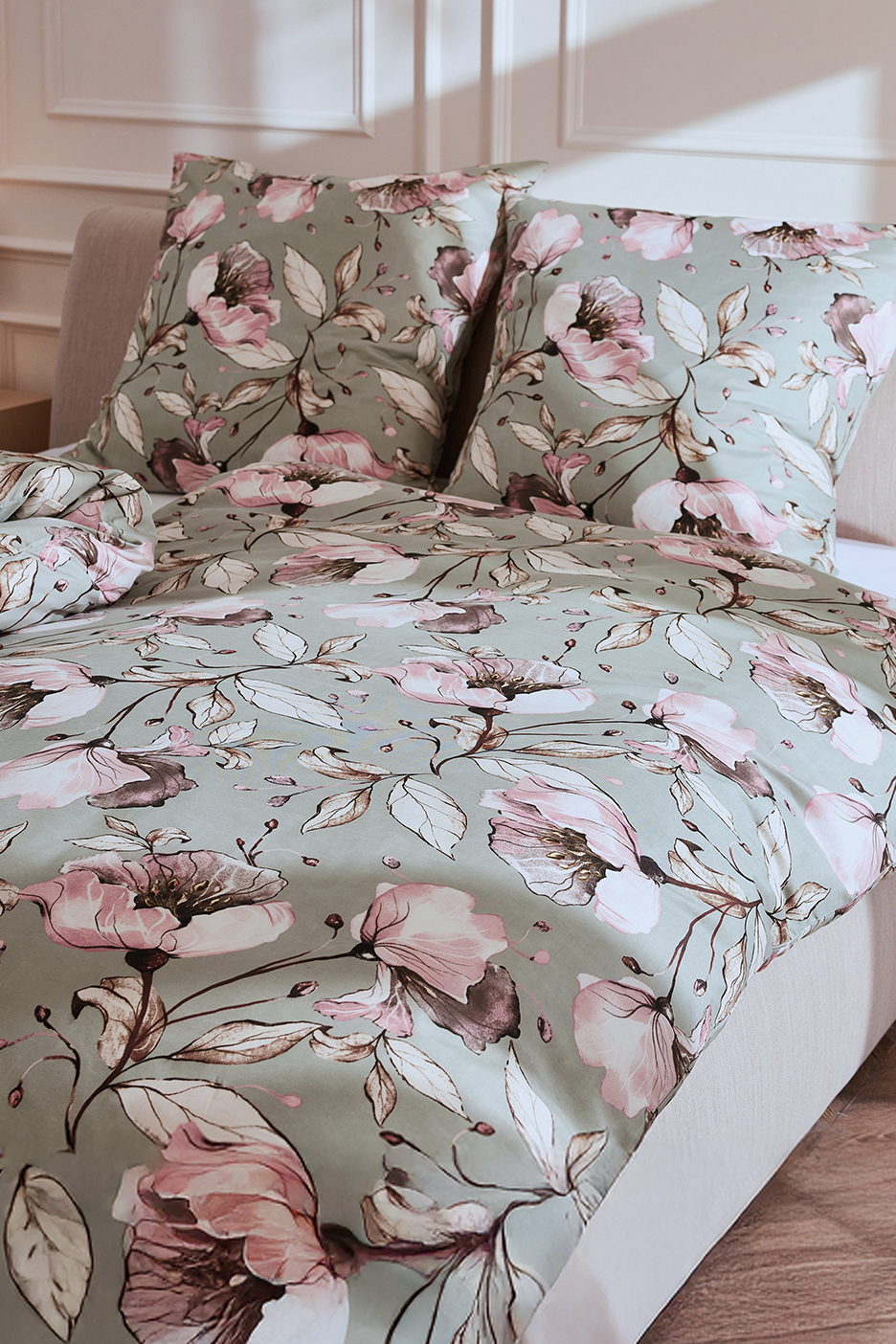 Virágmintás ágyneműhuzat és párnahuzatok halványzöld alapon, rózsaszín virágokkal.