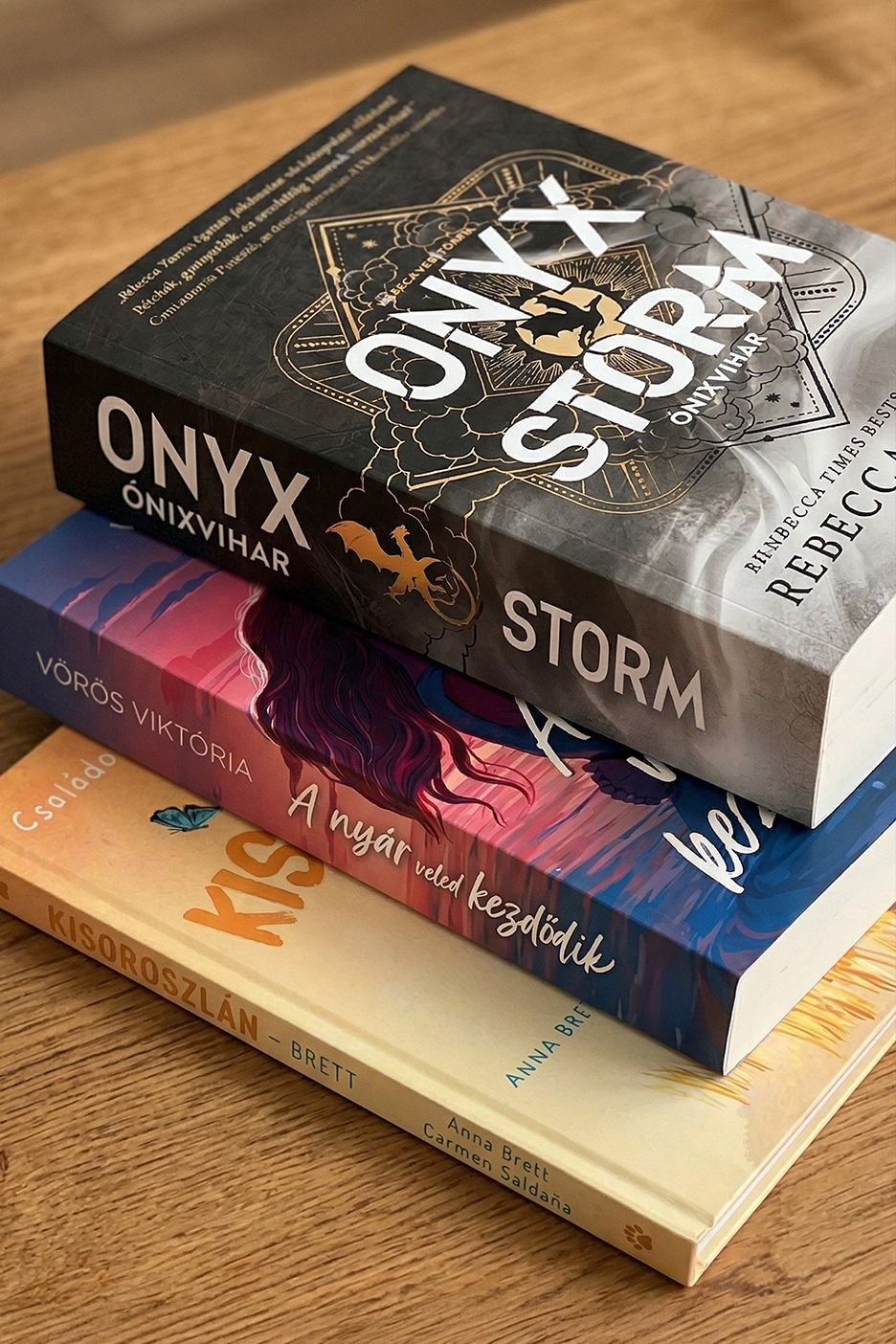 Három könyv, köztük egy fekete borítójú, arany díszítésű, „Onyx Storm” feliratú.