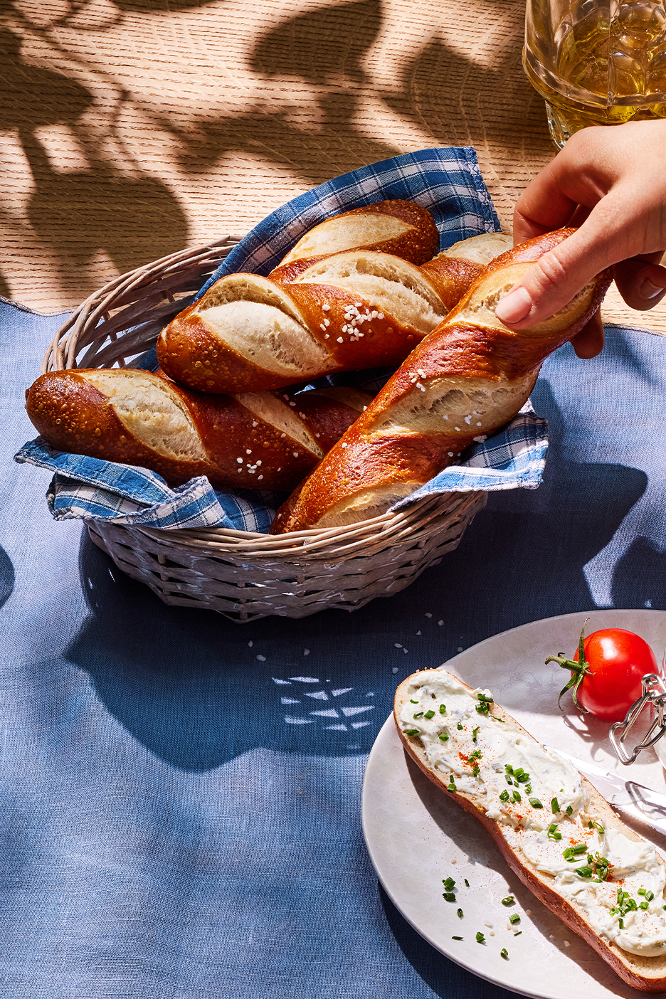 MI/AI segítségével létrehozott/módosított kép: Friss, sós perecrudak kosárban és egy megkent szelet tányéron, paradicsommal.