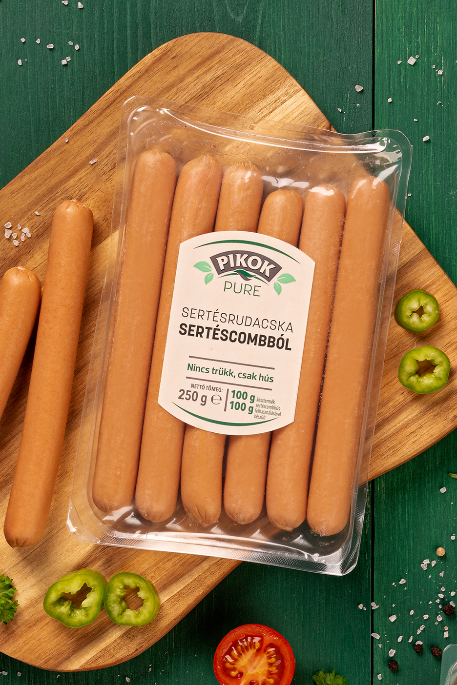 Pikok Pure sertésrudacskák csomagolásban, vágódeszkán, zöldségekkel.