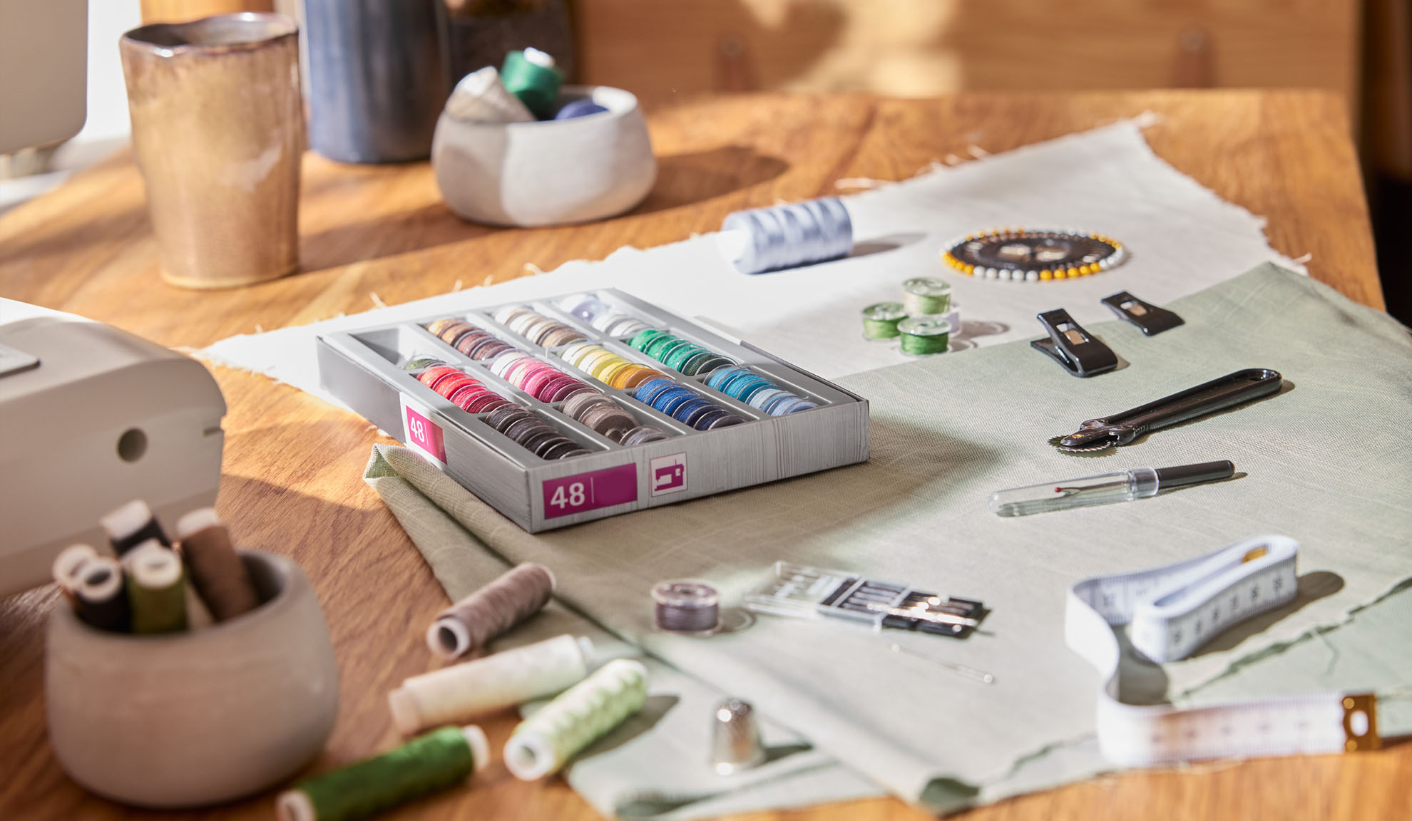 Varrókészlet színes cérnákkal, varrógéppel és eszközökkel egy fa asztalon.