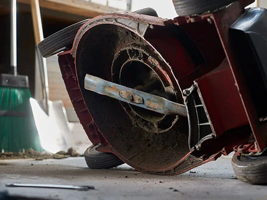 Piszkos fűnyíró fejjel lefelé, látható pengével