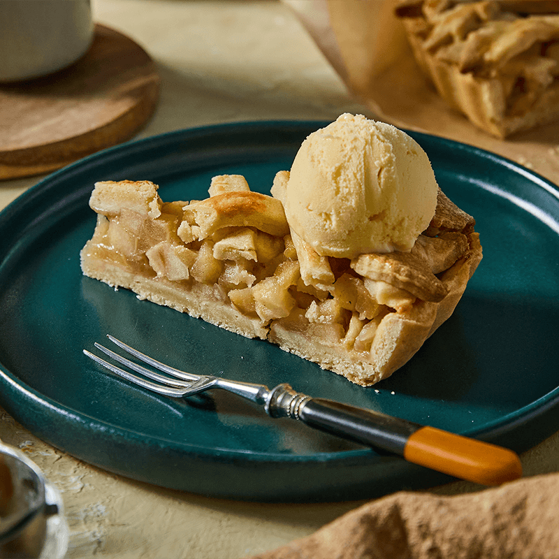 Almás pite vaníliafagyival egy sötétzöld tányéron, villával