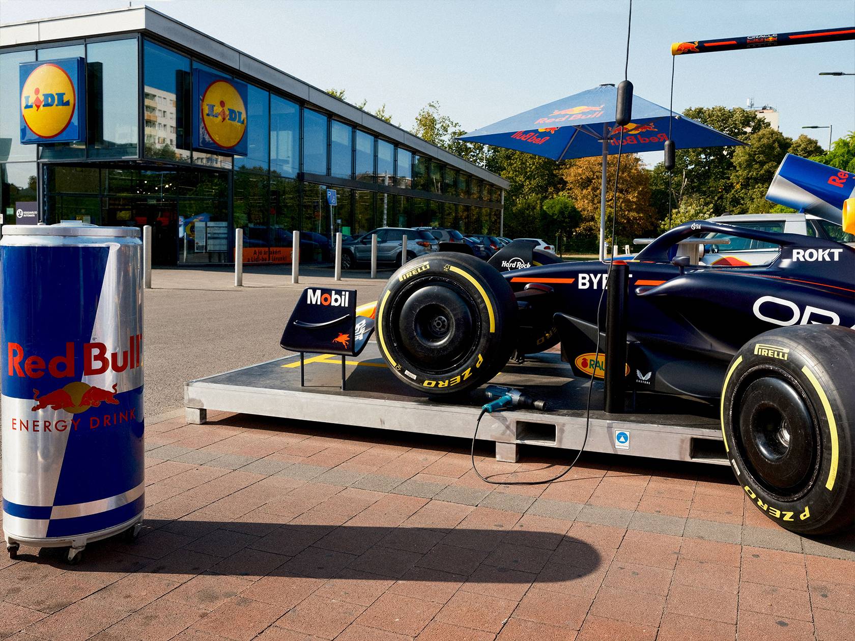 Red Bull energiaital és egy Red Bull Racing Formula 1-es autó egy Lidl áruház előtt.