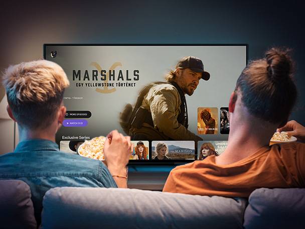 Két férfi néz filmet a tévében, miközben pattogatott kukoricát esznek.