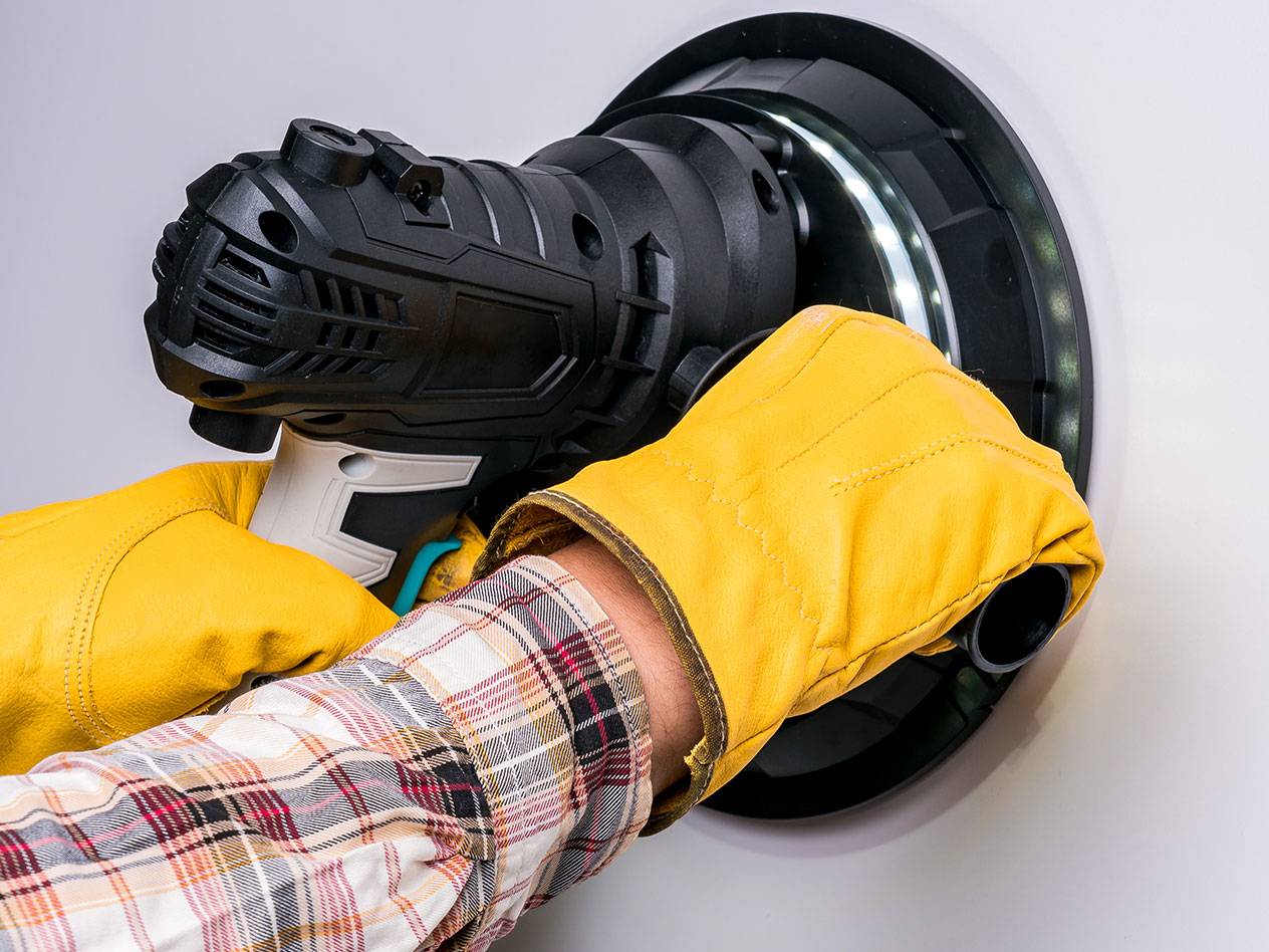 Elektromos falcsiszoló LED világítással, kesztyűt viselő személy használja.
