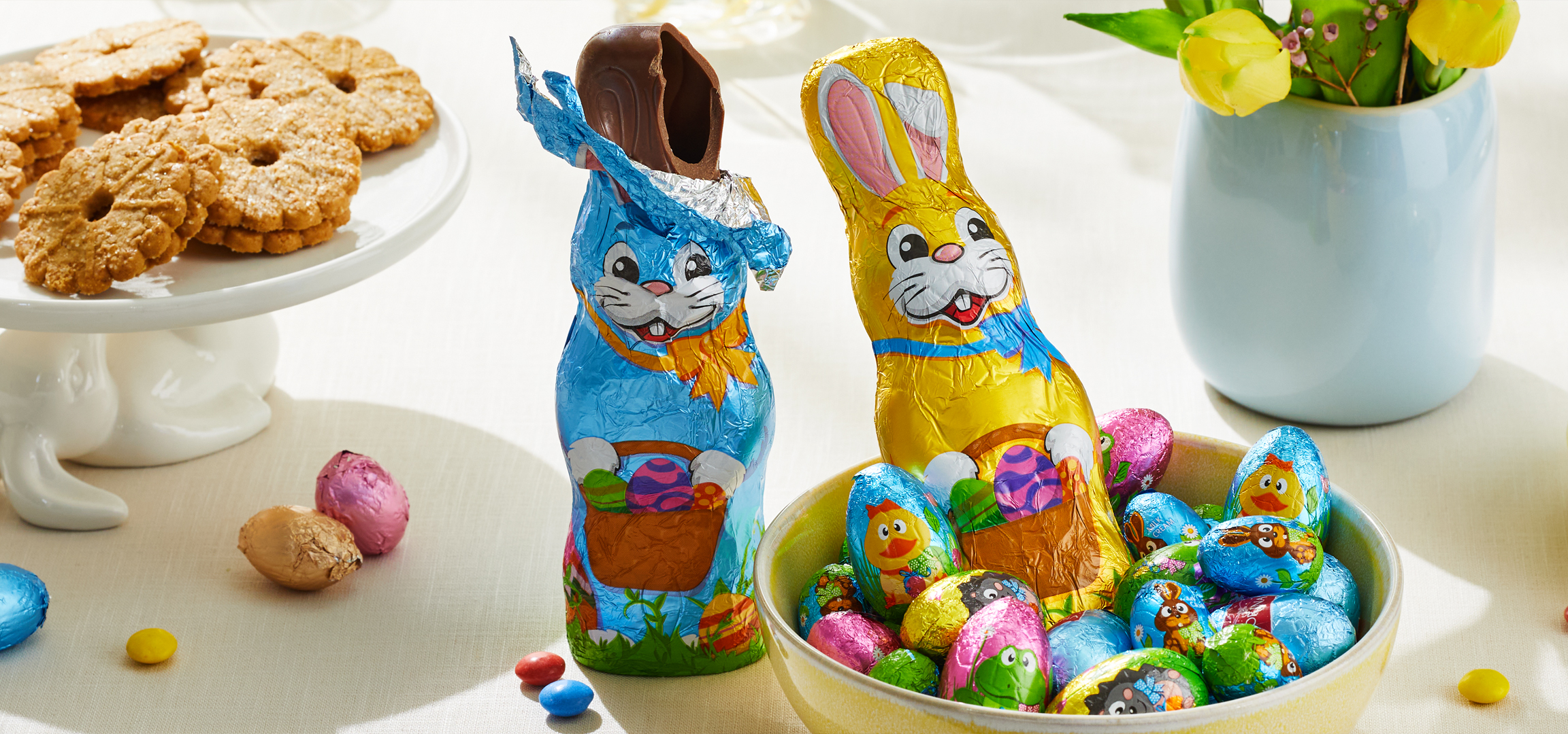 Húsvéti asztal csokinyuszikkal, csokitojásokkal, cukorkákkal és kekszekkel.