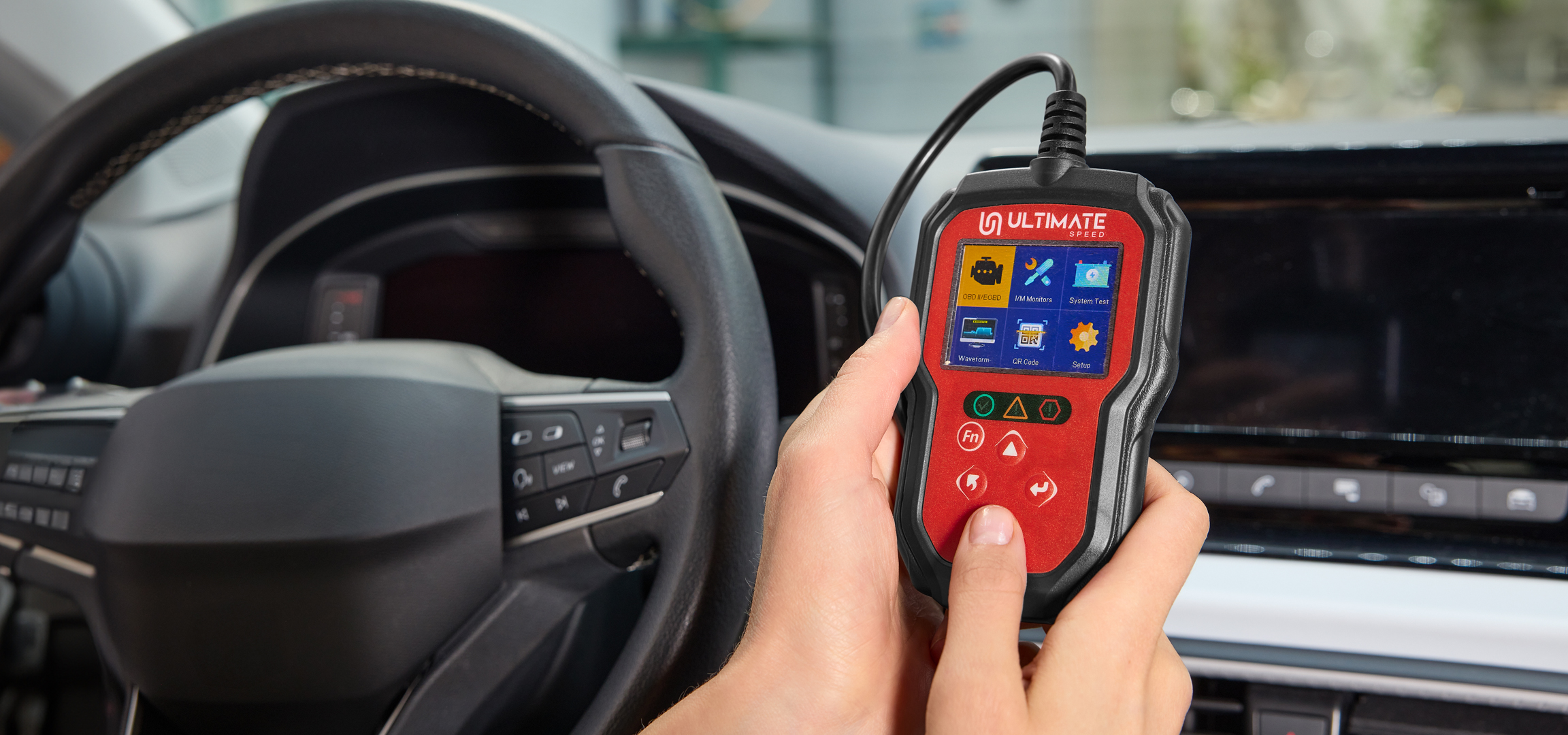 Kézi diagnosztikai eszköz autóban, a kormánykerék és a műszerfal előtt.