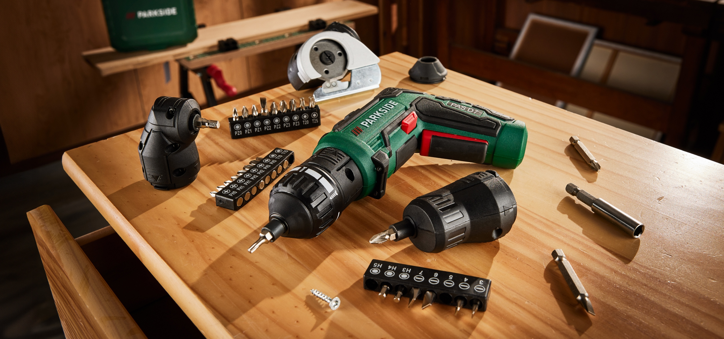 Akkus csavarhúzó és fúrószárkészlet egy fa asztalon, műhelykörnyezetben.