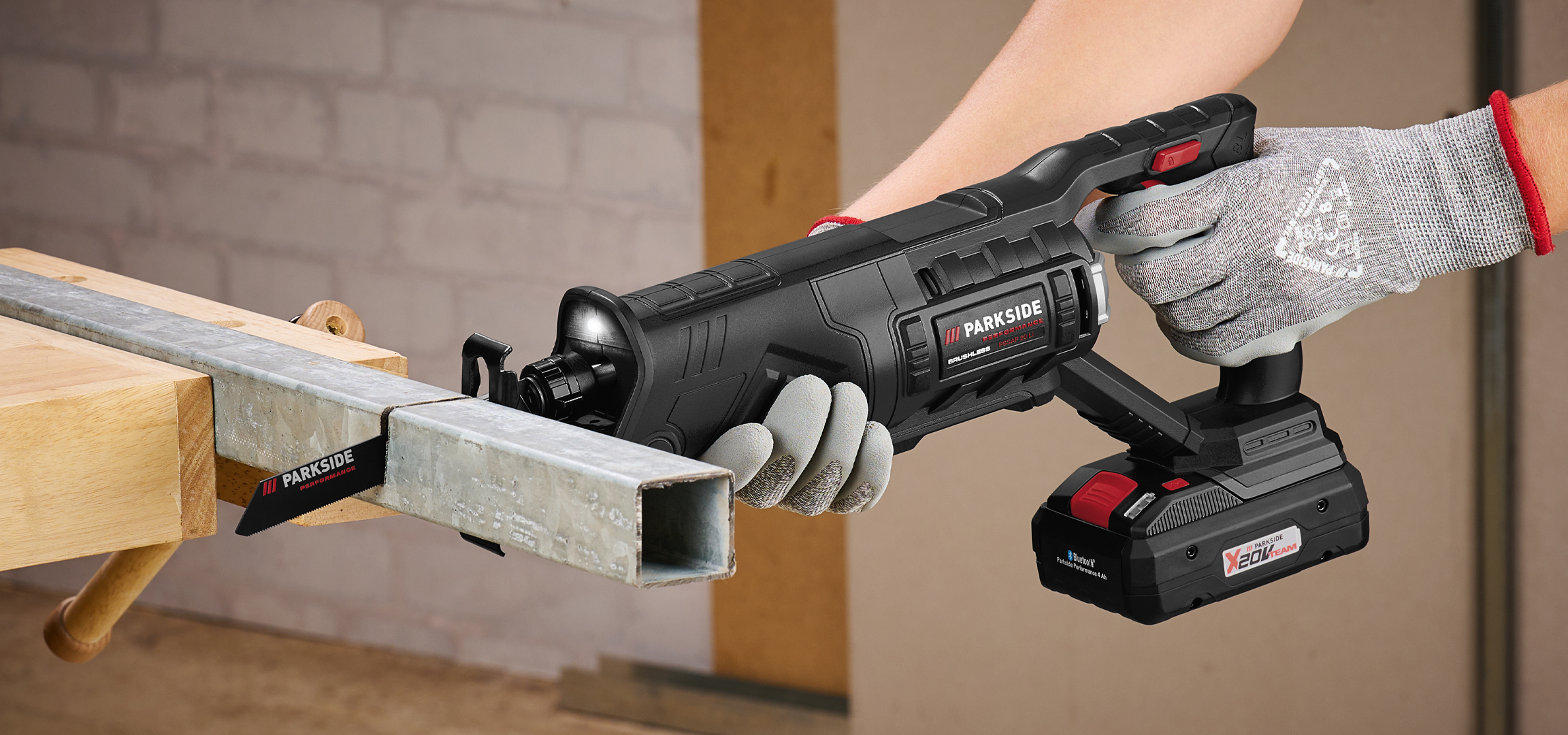 Fűrészgép fémcső vágására, munkapadon rögzítve, védőkesztyűben tartva.