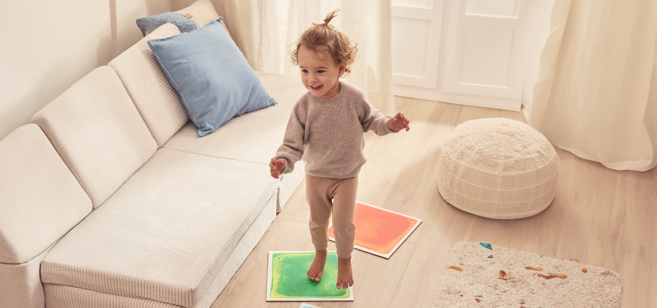 Egy kisfiú játszik a nappaliban, folyékony padlólapokon állva.