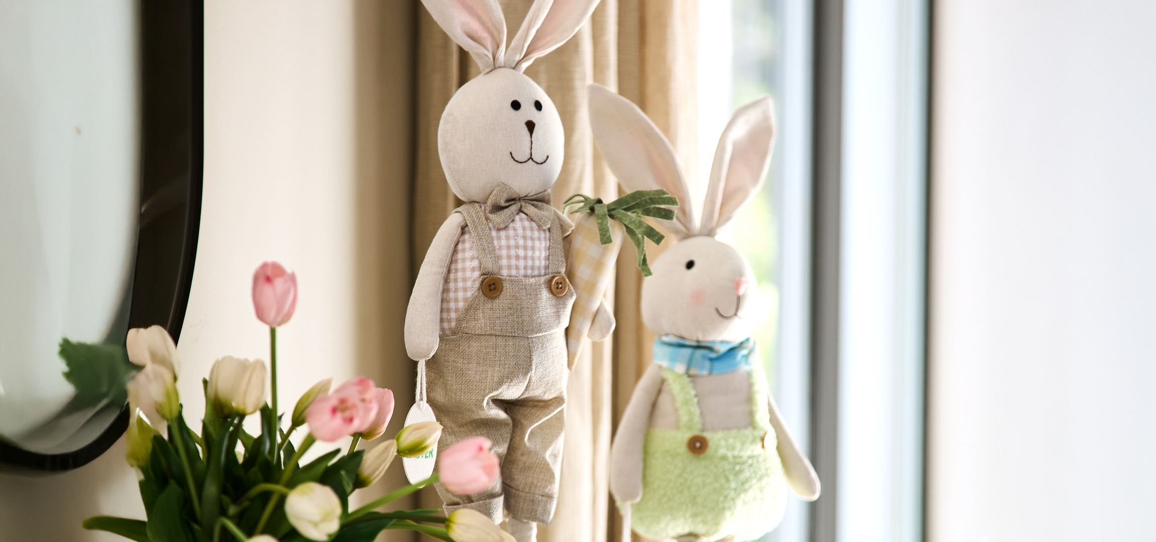 Húsvéti nyuszik és rózsaszín tulipánok egy ablak előtt.