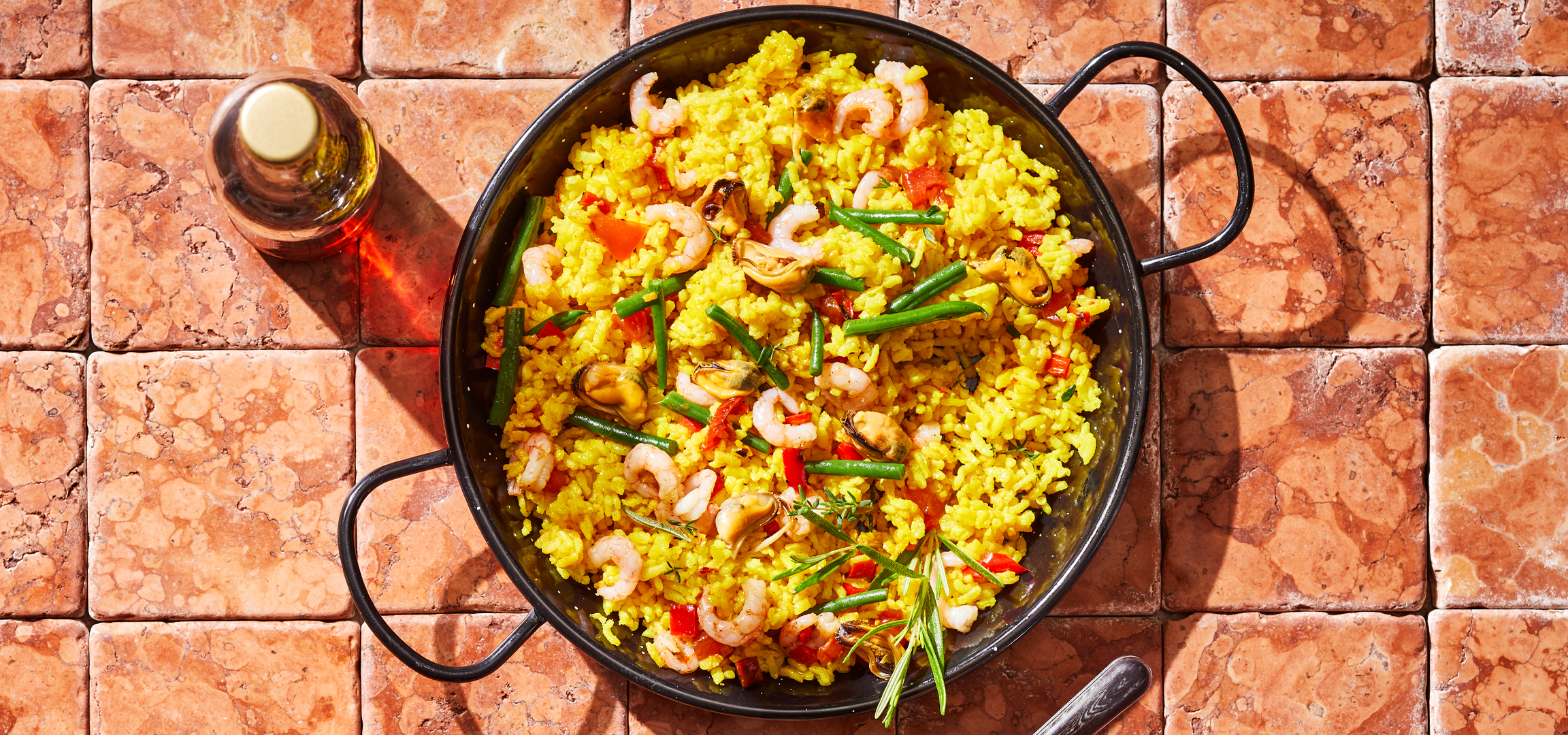 Paella serpenyőben, olajjal egy csempézett asztalon, felülről nézve.