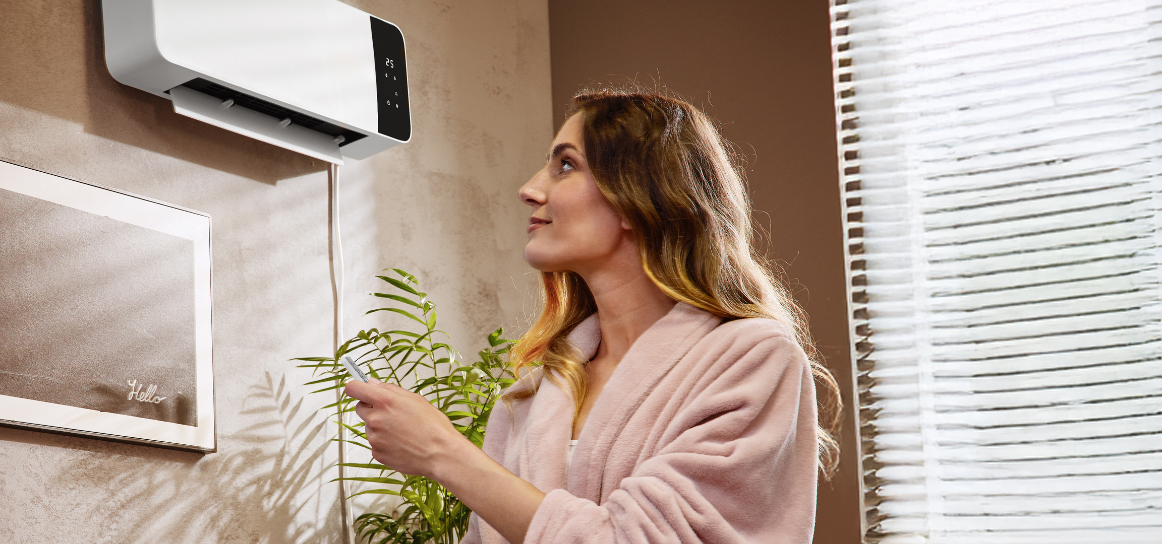 Nő fürdőköpenyben, légkondicionálóval és szobanövénnyel