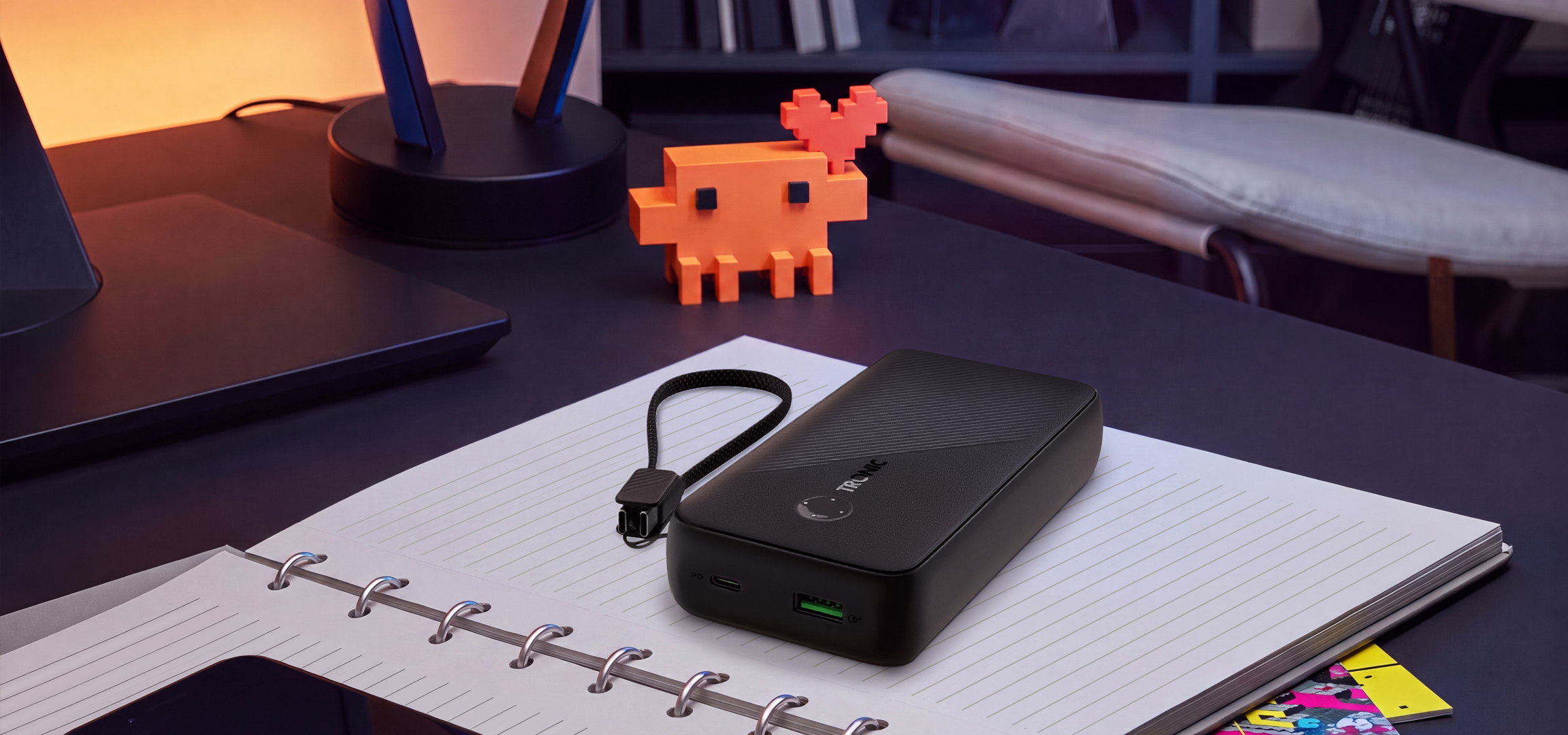 MI/AI segítségével létrehozott/módosított kép: Fekete powerbank és okostelefon egy jegyzetfüzeten az íróasztalon.