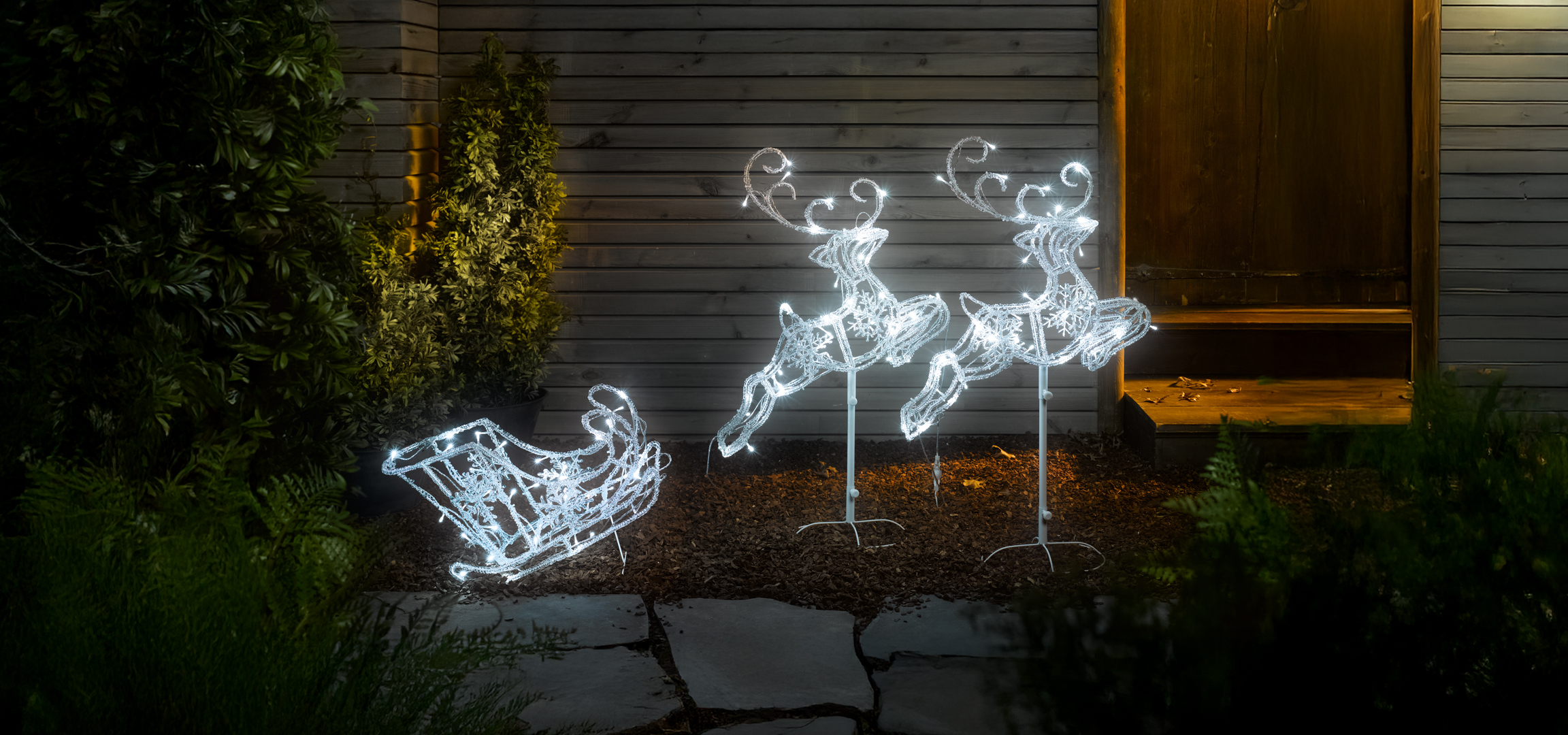 Világító karácsonyi rénszarvasok és szán a kertben