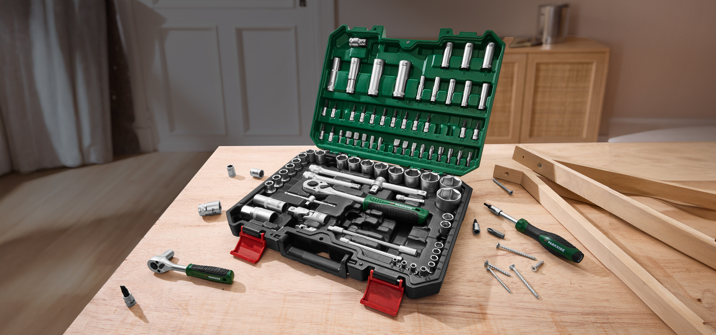 Parkside szerszámkészlet racsnis kulcsokkal, csavarhúzóval és csavarokkal egy fa asztalon.