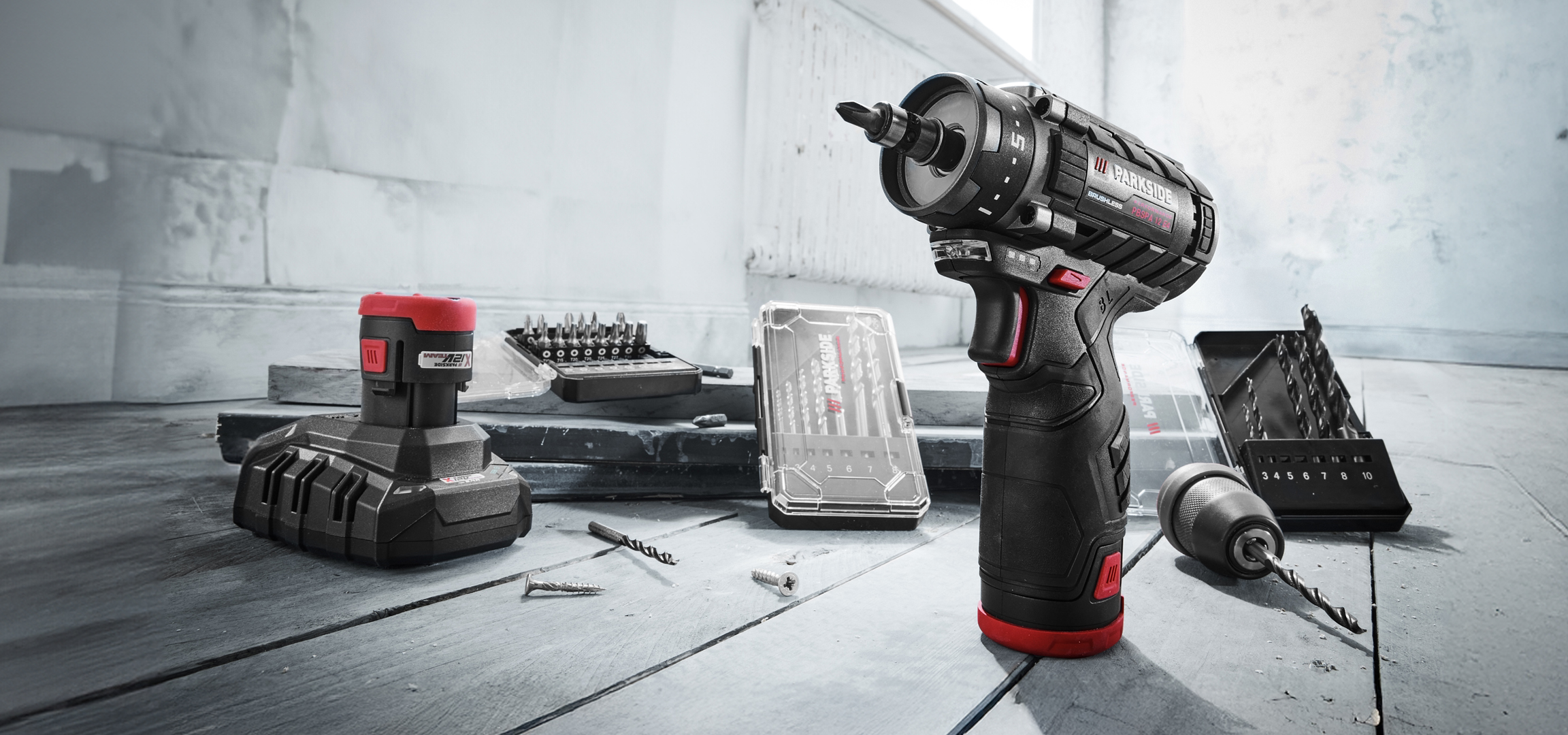 Parkside akkus fúró-csavarozó, akkumulátor és bitkészletek egy munkapadon.
