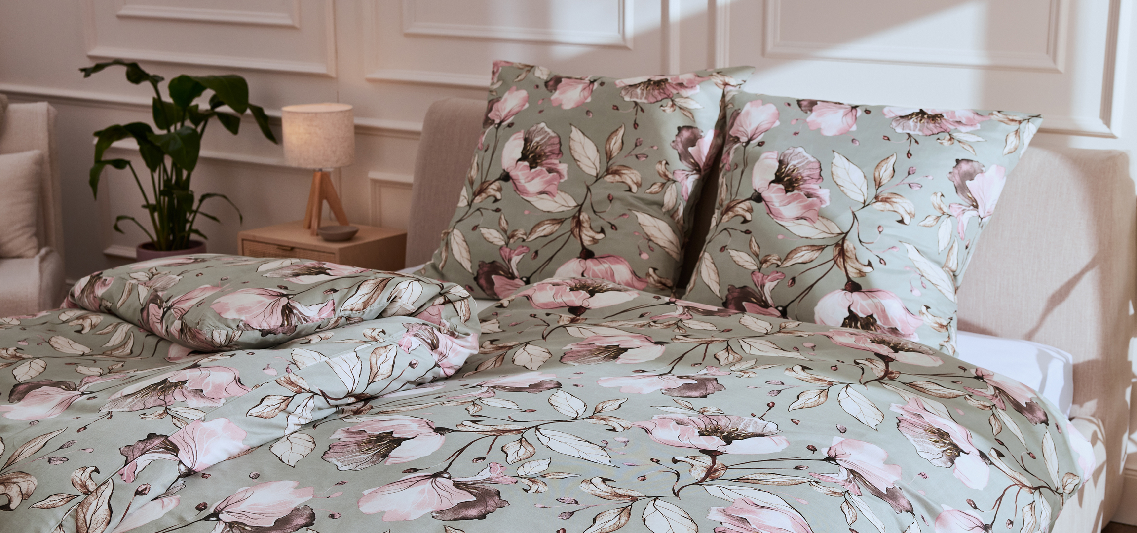 Virágmintás ágyneműhuzat és párnák egy hálószobában, kanapéval és növényekkel.