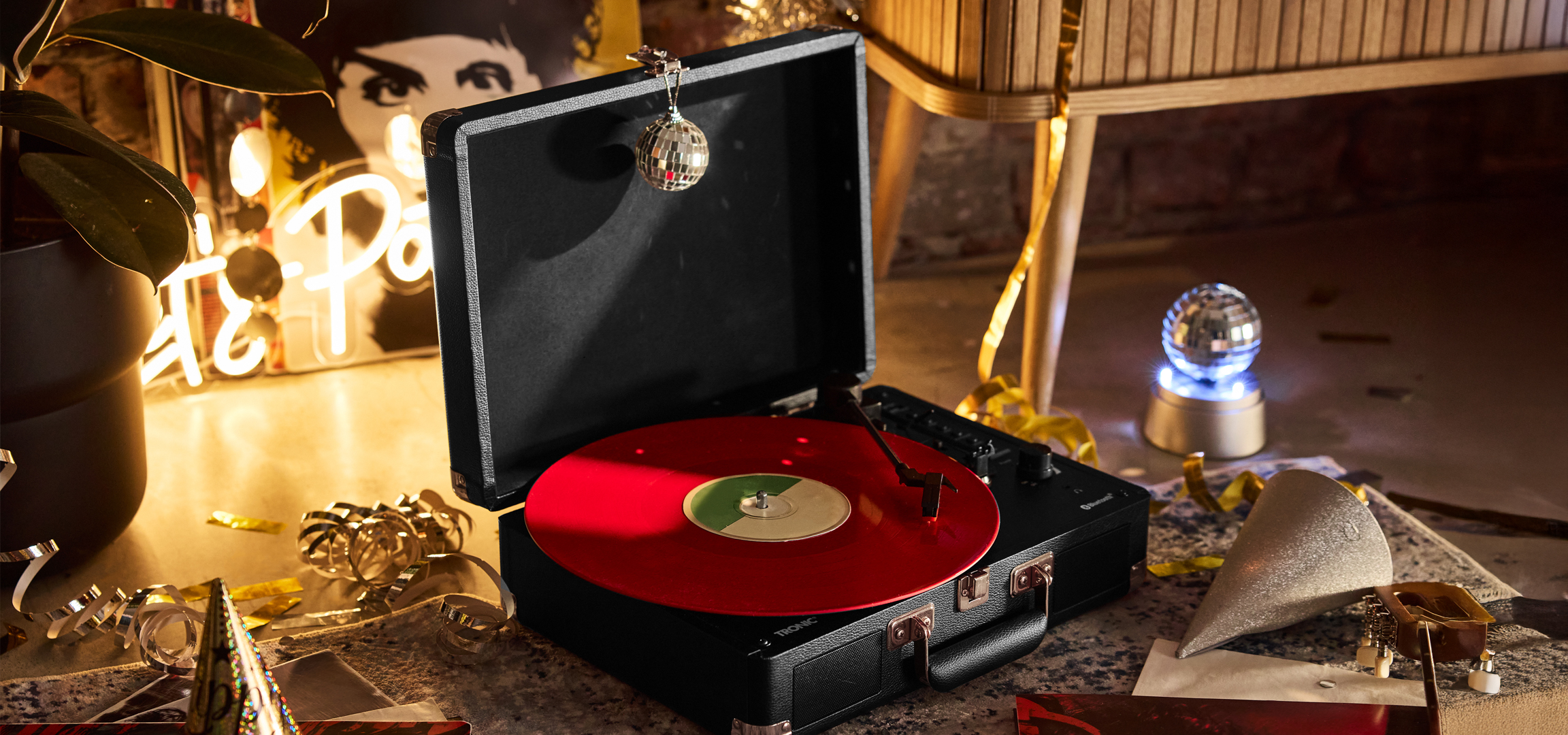 Lemezjátszó piros lemezzel, diszkógömbökkel és parti dekorációval, csillagos égbolt háttérrel.