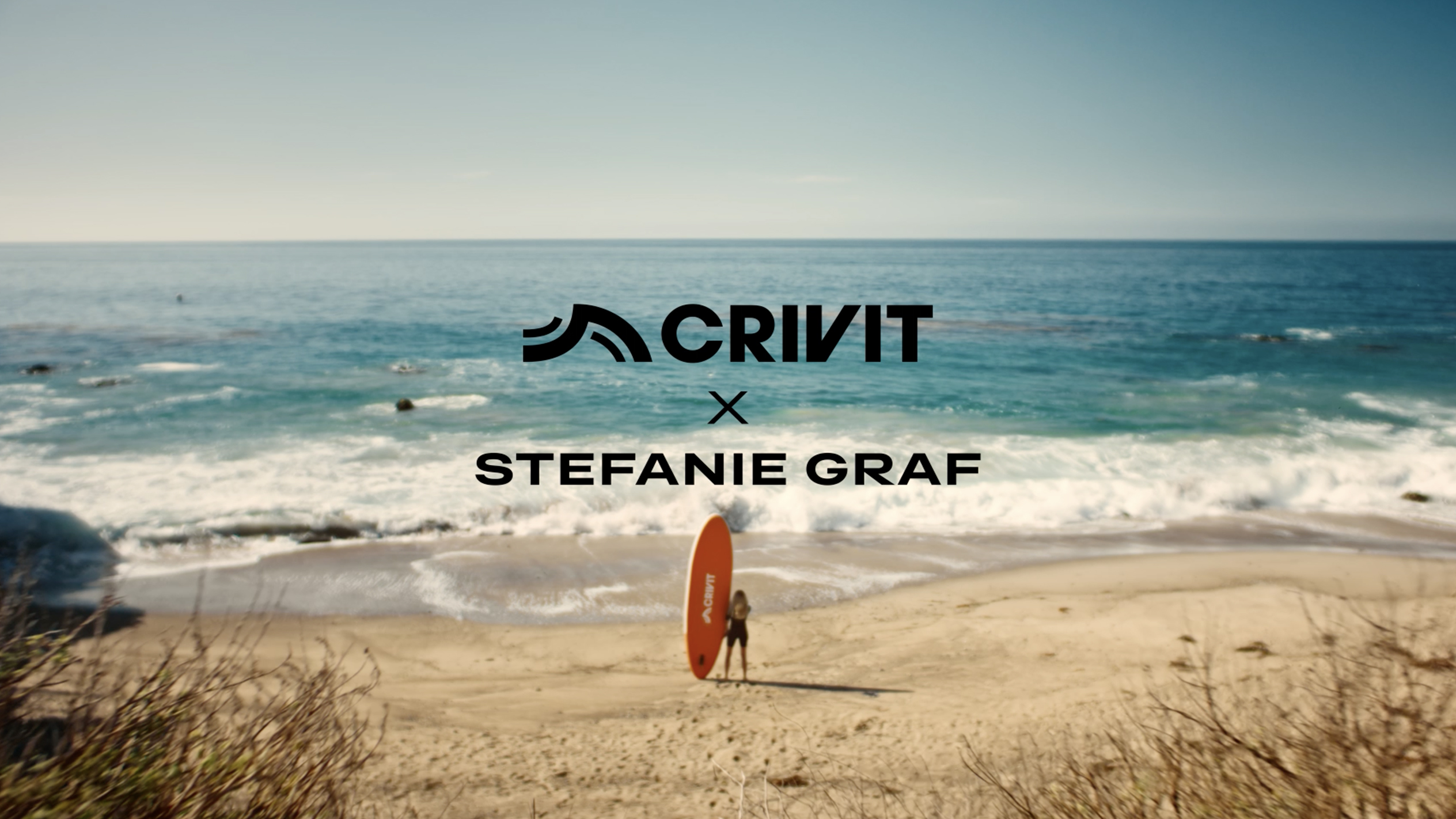 Nő narancssárga SUP deszkával homokos tengerparton, háttérben a tengerrel.