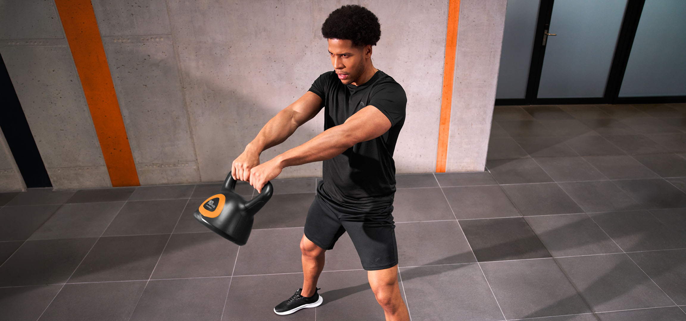 MI/AI segítségével létrehozott/módosított kép: Férfi edz egy fekete-narancssárga kettlebell súlyzóval.