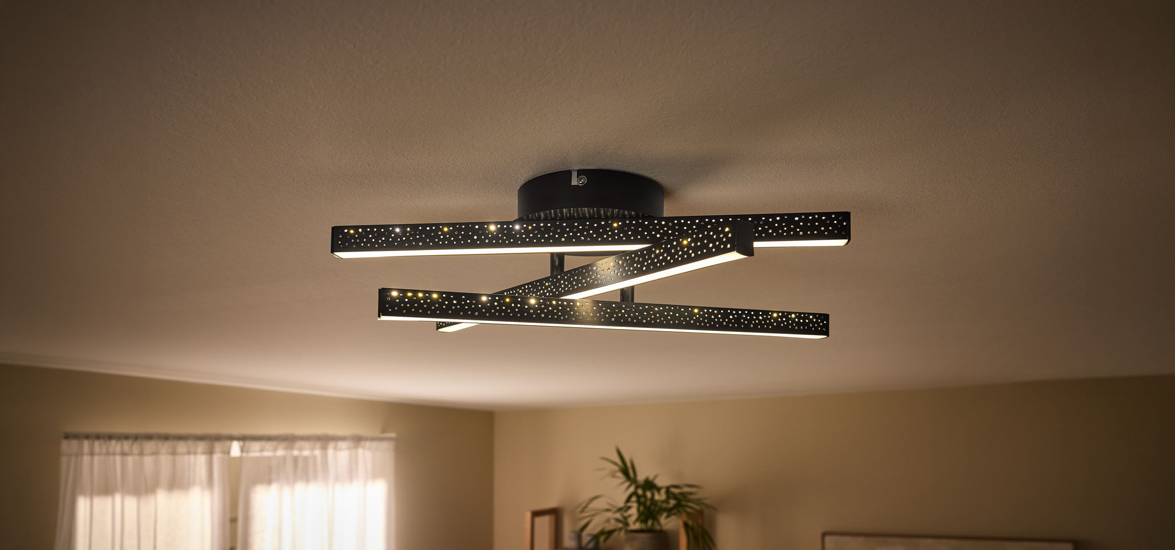 Modern LED mennyezeti lámpa fekete, perforált rudakkal és meleg fénnyel.