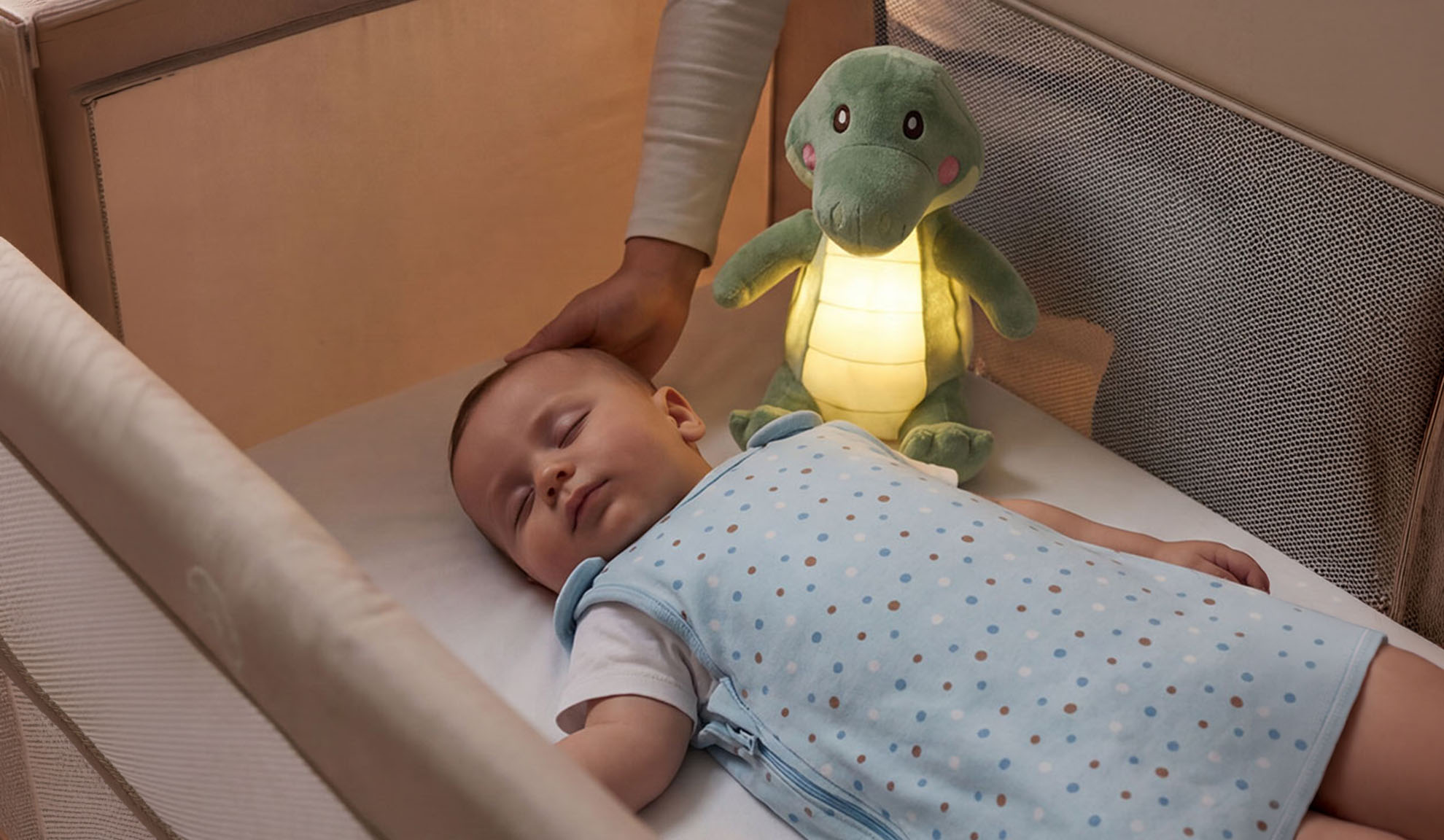 Baba alszik kiságyban plüssjátékkal és szülői kézzel.