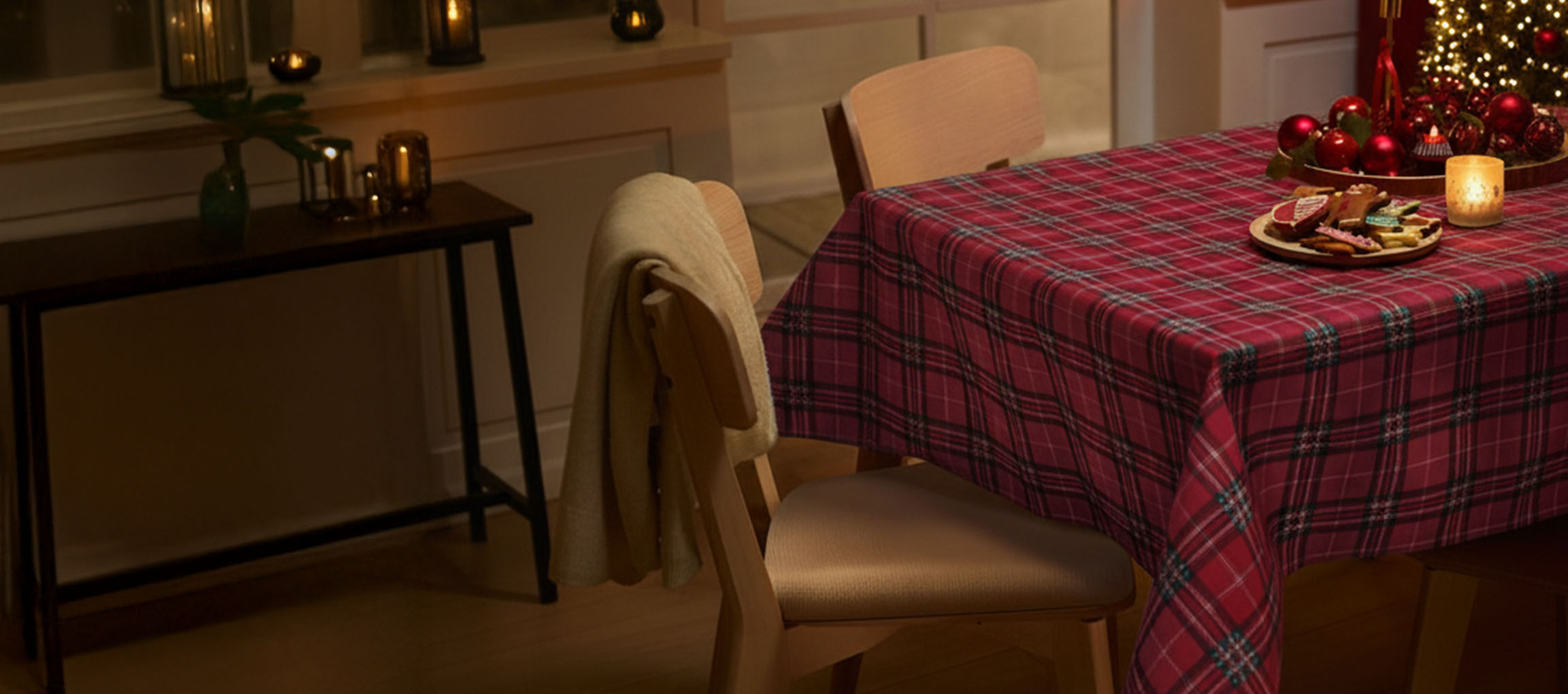 Karácsonyi teríték piros kockás terítővel, székekkel és karácsonyi sütikkel.